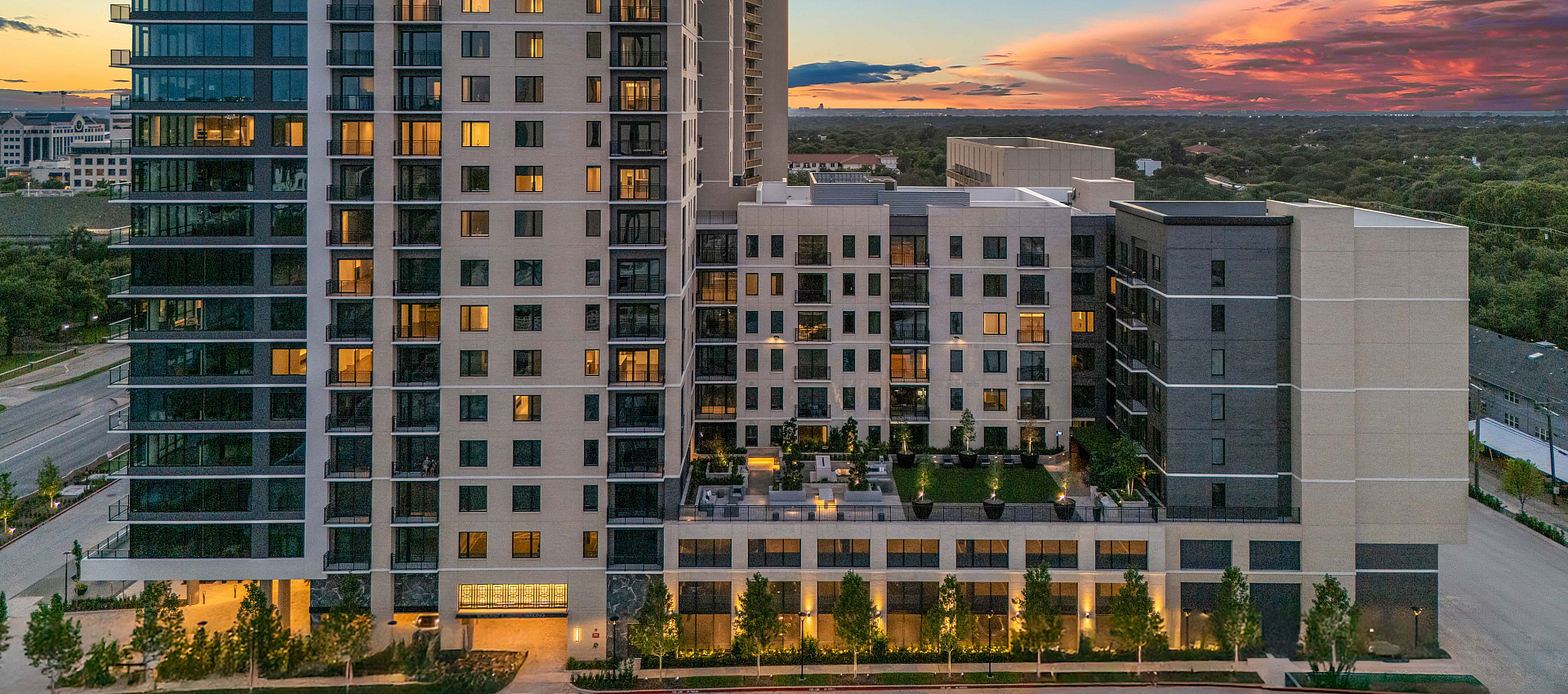 Stunning urban apartment complex at sunset featuring modern architecture and vibrant lighting.