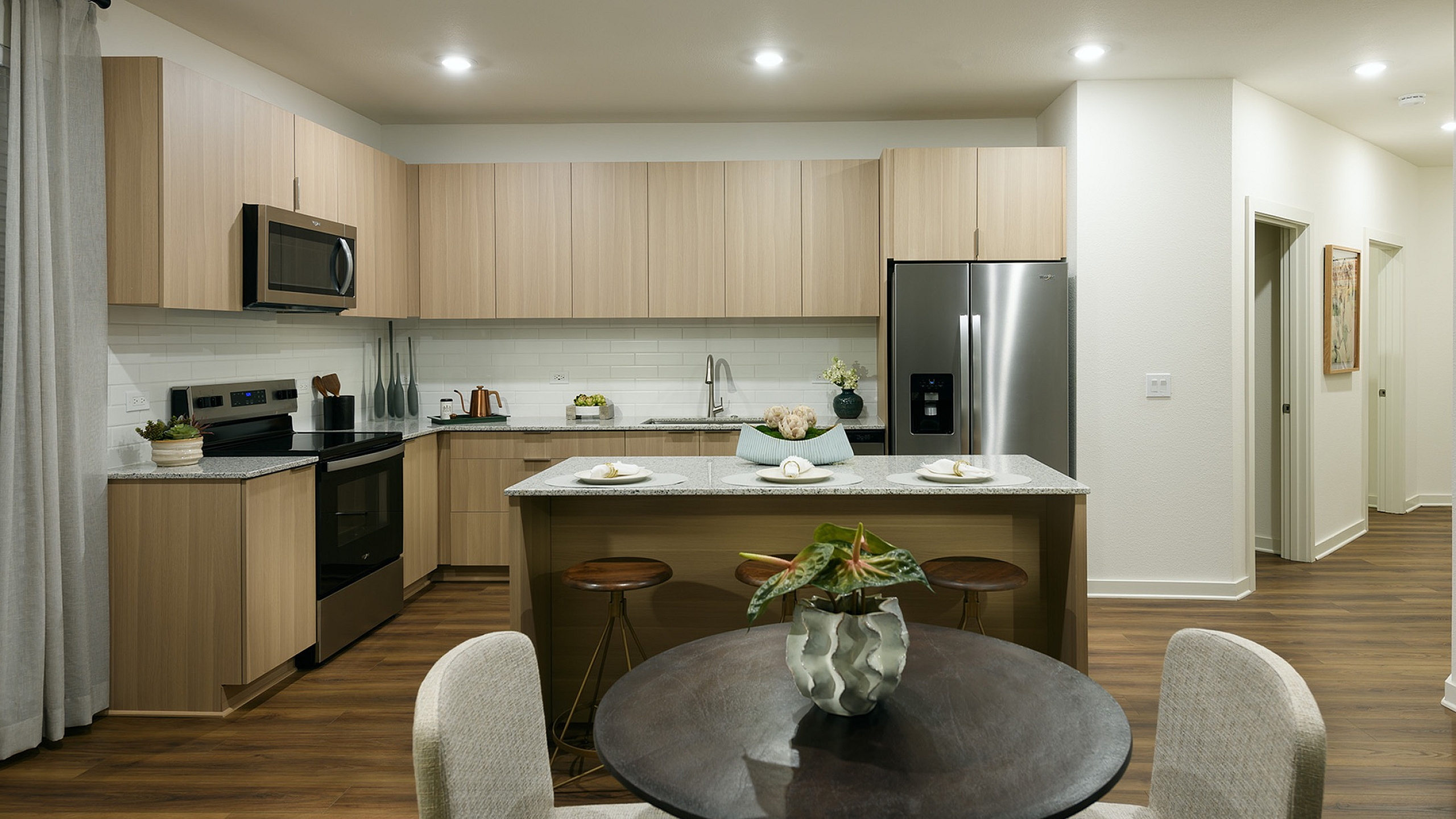 Contemporary kitchen with sleek light wood cabinetry, stainless steel appliances, and elegant dining area.