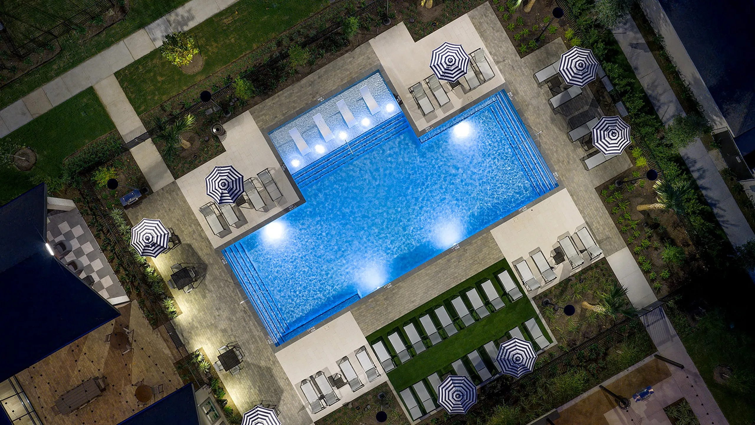 Elegant aerial view of a luxurious swimming pool surrounded by stylish lounge chairs and chic umbrellas, perfect for relaxation and leisure.