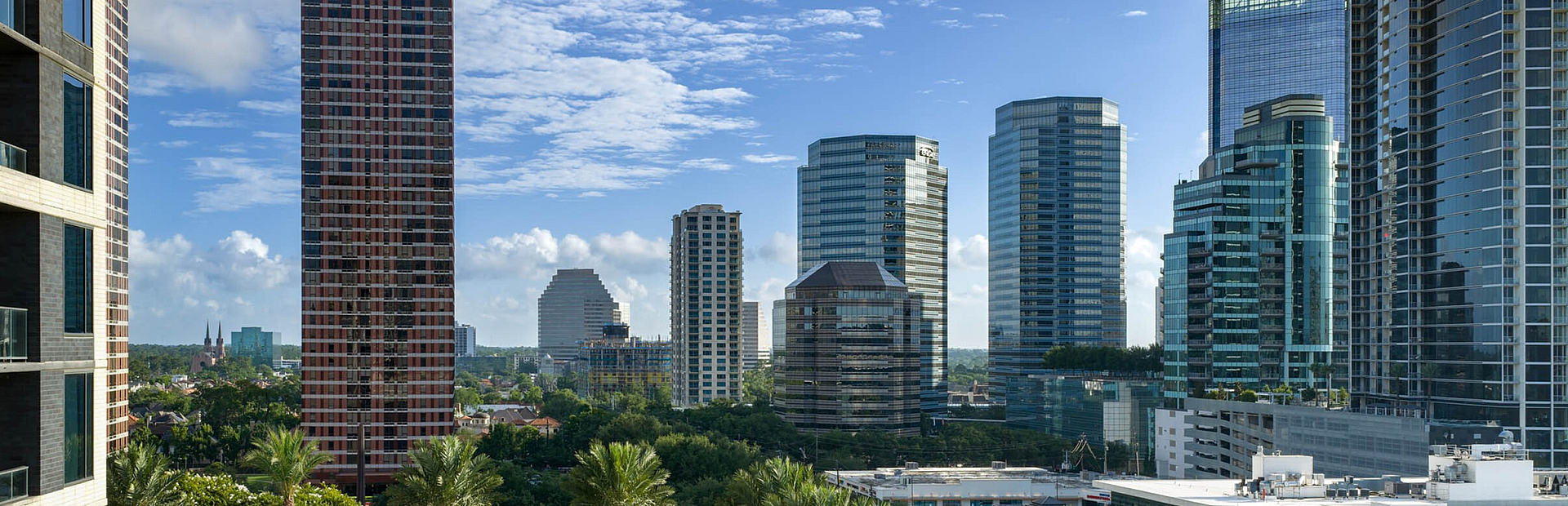Scenic urban view showcasing a luxurious pool area surrounded by lush greenery, with modern skyscrapers under a bright blue sky.