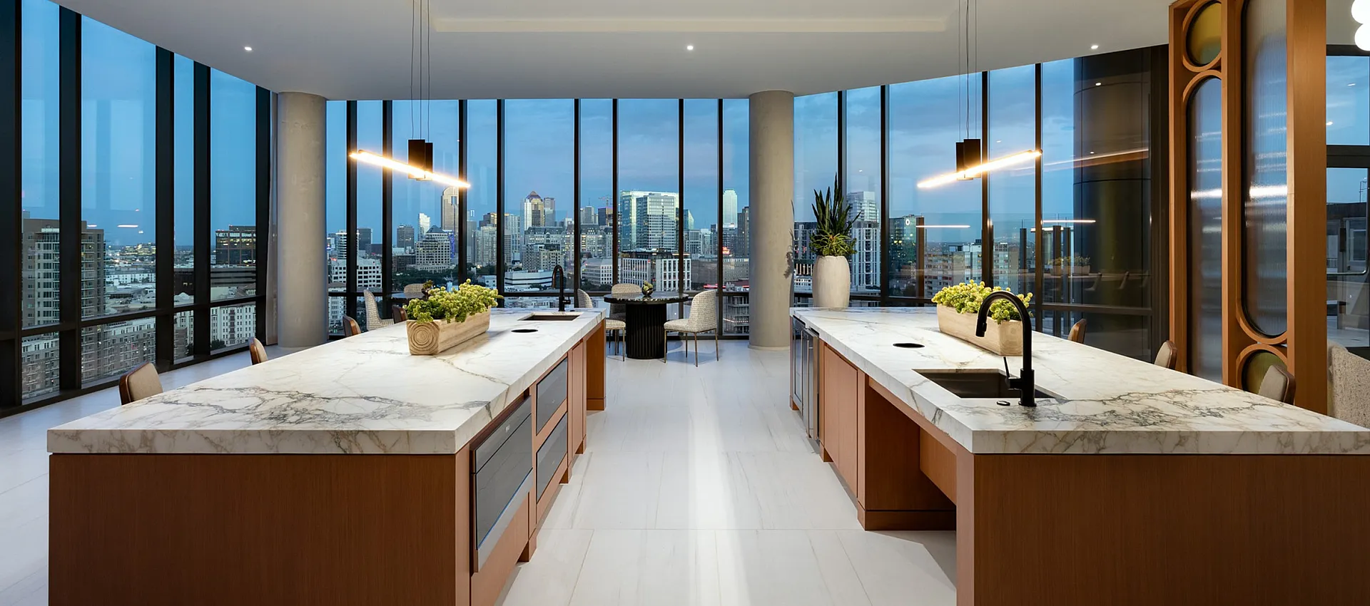Luxurious open-concept kitchen with sleek marble countertops, elegant lighting, and panoramic cityscape views through expansive floor-to-ceiling windows.