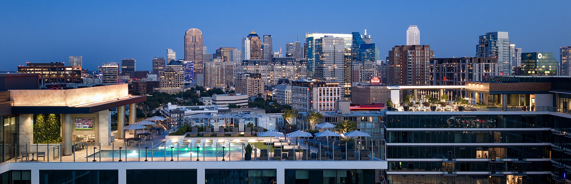 Luxurious rooftop terrace with a sparkling pool overlooking a vibrant city skyline at dusk.
