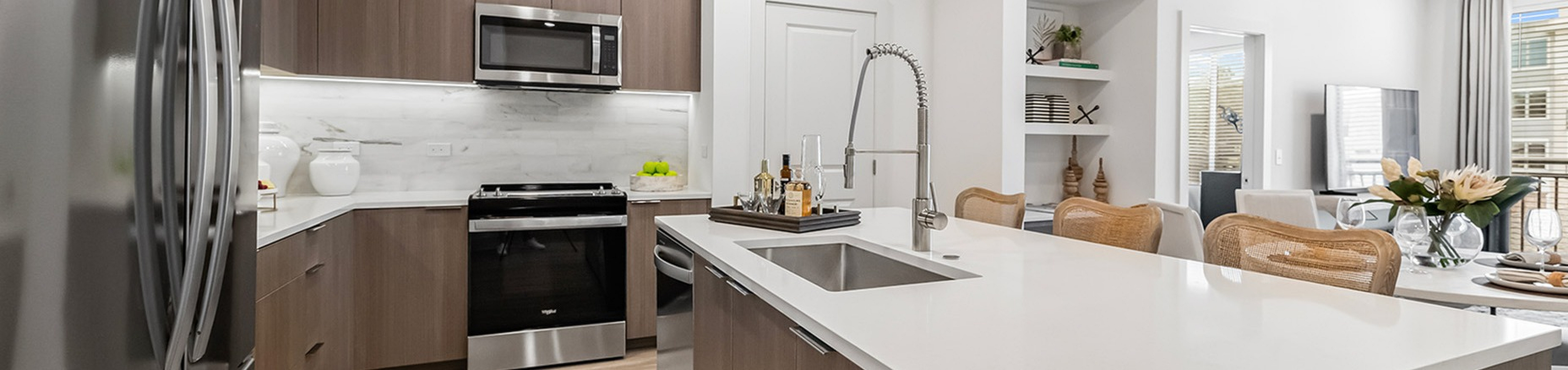 Modern kitchen with sleek cabinets, stainless steel appliances, and a spacious island, seamlessly connecting to a bright dining area with elegant decor.