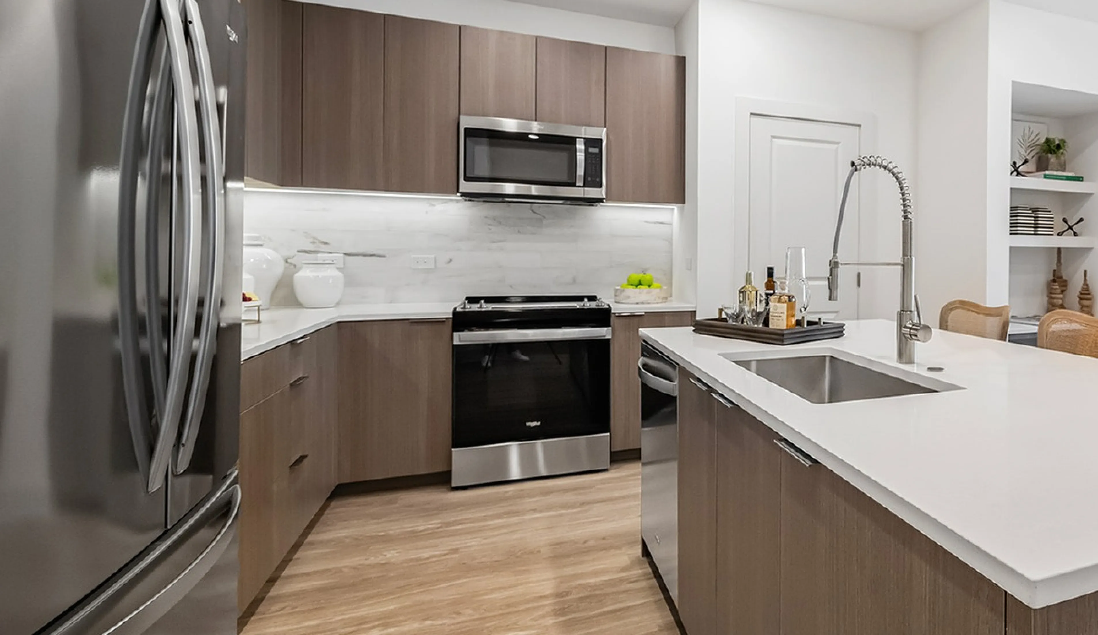 Contemporary kitchen with sleek stainless steel appliances, elegant wood cabinetry, and a spacious island counter, flowing into an inviting dining area with abundant natural light.
