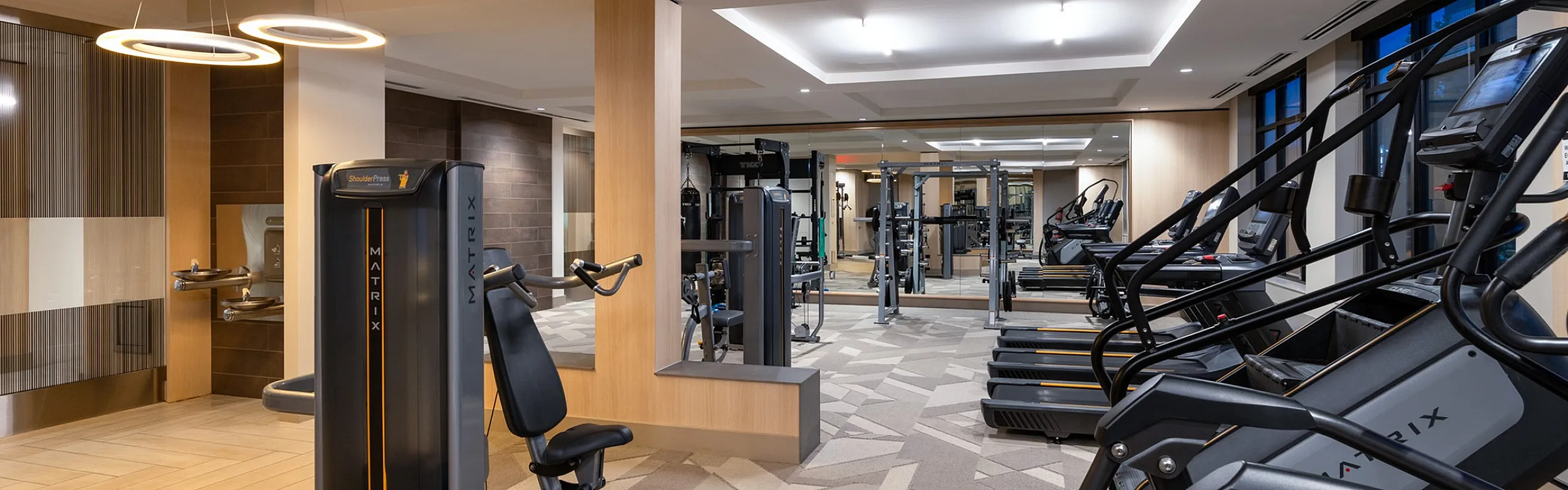Modern fitness center featuring state-of-the-art equipment, sleek elliptical machines, and warm ambient lighting.