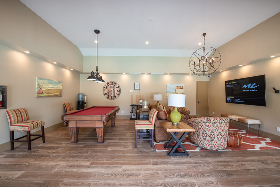 Luxurious recreation room with elegant pool table, cozy seating, and stylish decor featuring soft lighting and a large wall-mounted TV.