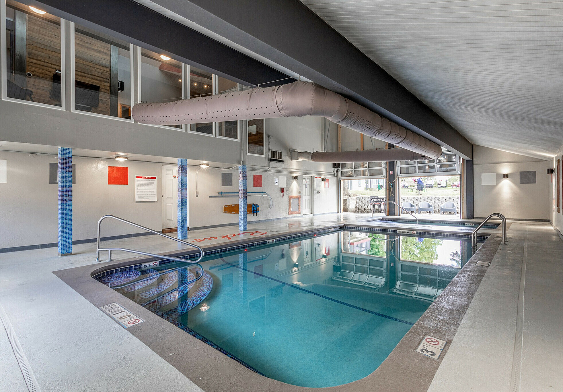 Luxurious indoor swimming pool with sleek design and ample natural lighting.