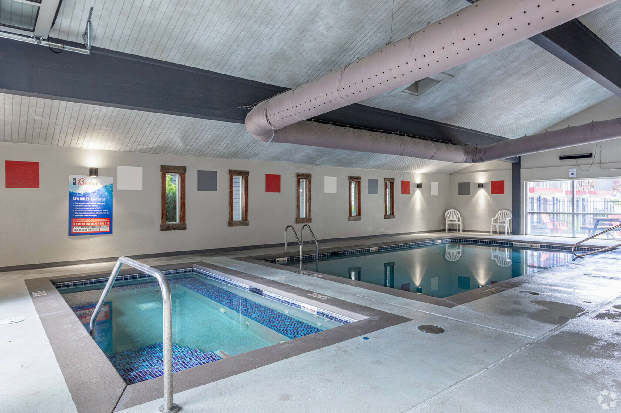 Inviting indoor pool area featuring a swimming pool and hot tub, accompanied by modern decor and natural light.