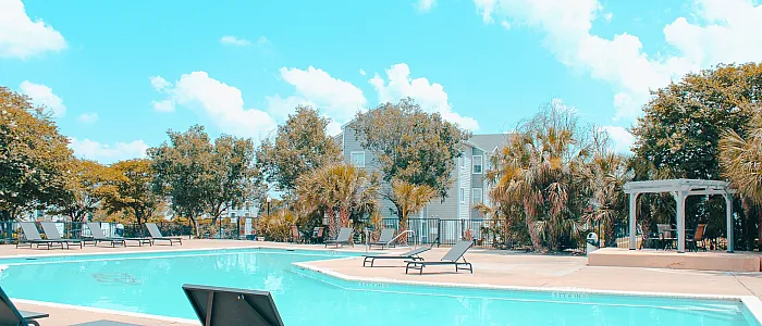 Inviting outdoor pool area with stylish lounge chairs and lush greenery, perfect for relaxation and leisure.