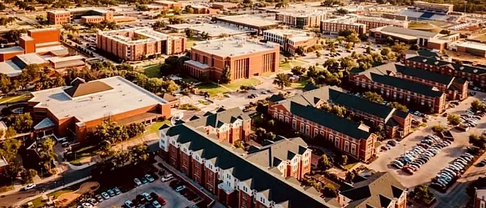 Aerial view of a vibrant urban neighborhood with charming red-brick buildings, lush greenery, and ample parking, perfect for city living.