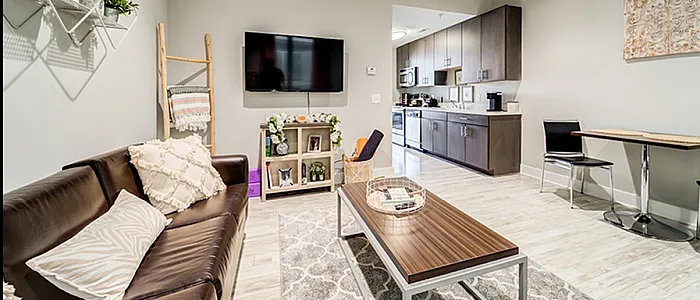 Modern open-concept living space with a sleek kitchen, cozy living room featuring a large TV and stylish decor, complemented by a chic dining area.