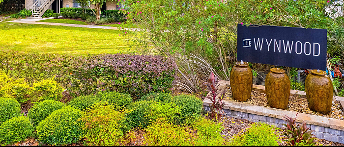 Charming garden view of The Wynwood with lush greenery, palm trees, and a welcoming entrance.