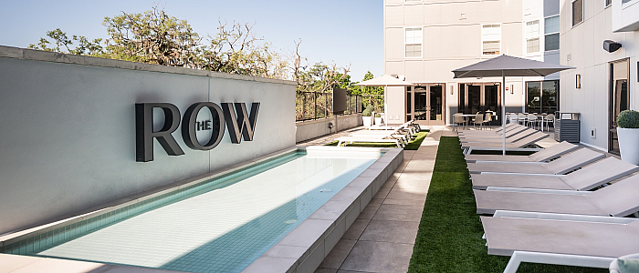Modern apartment complex featuring a sleek poolside area with sun loungers and stylish outdoor seating at The Row.