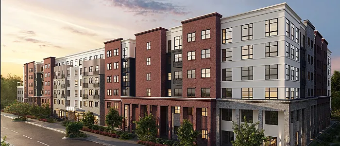 Contemporary urban apartment complex with a blend of classic red brick and modern white facade, showcasing expansive windows and landscaped surroundings at sunset.