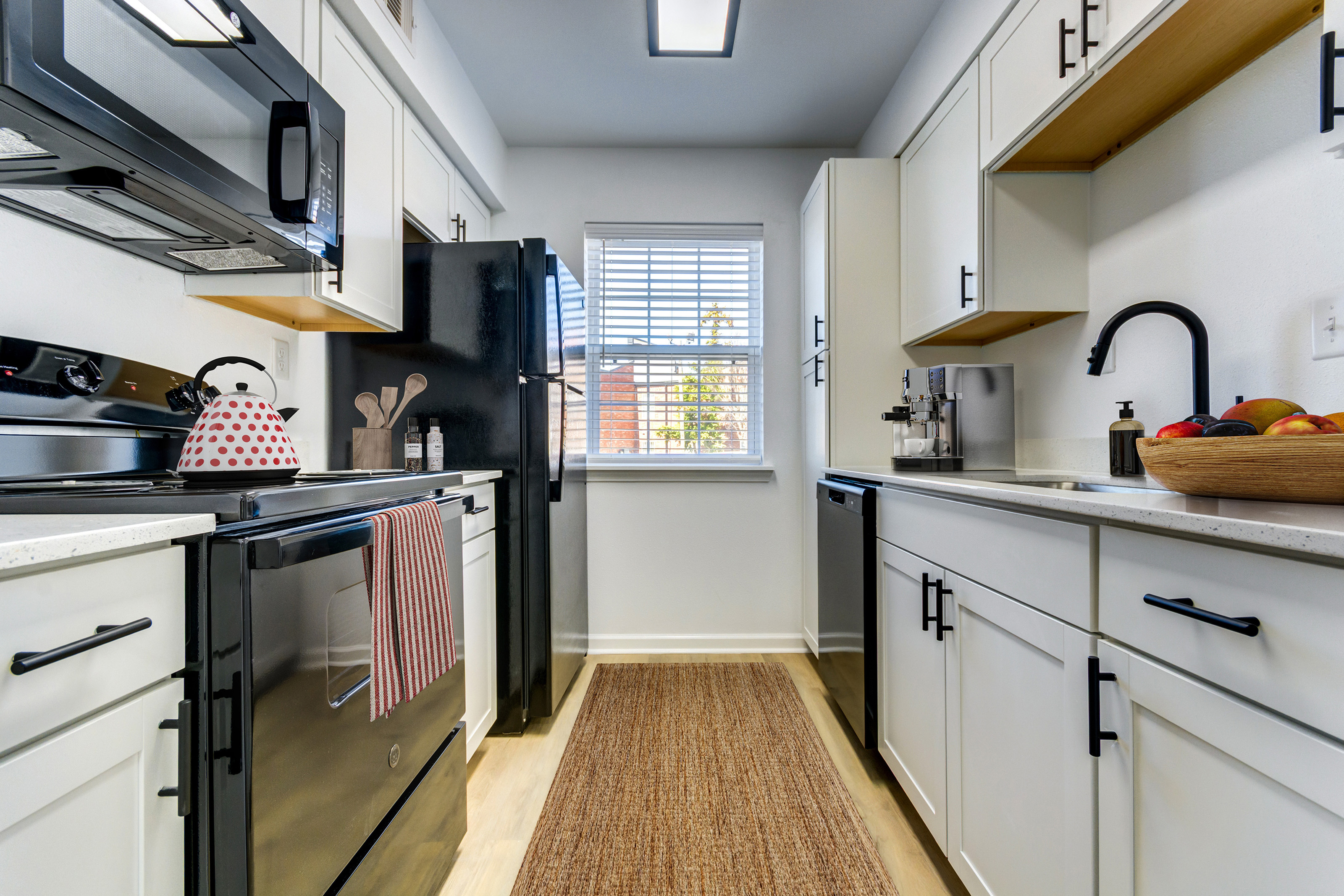 Chic upgraded kitchen with white cabinets and black appliances and black finishes, complemented by a bowl of fresh fruit on the counter