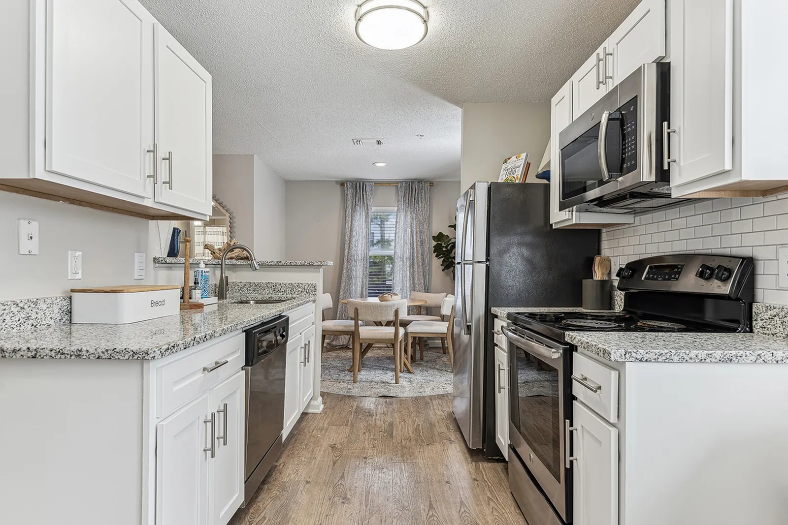 Renovated kitchen at ReNew Marina Shores with quartz countertops, stainless steel appliances, and white shaker cabinets