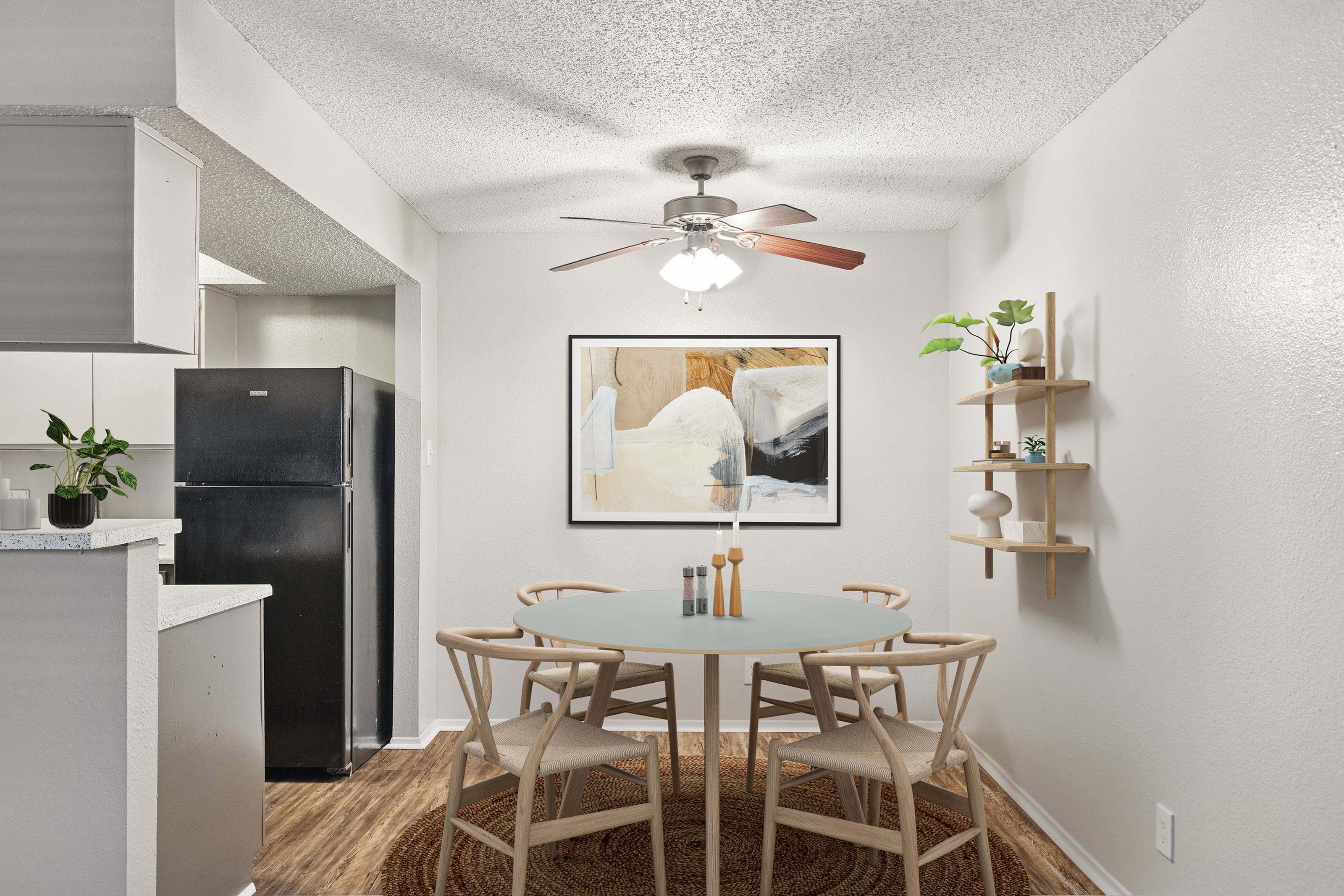 Dining room at ReNew Heights with view of kitchen with black appliances. Dining room has modern dining table and chairs.