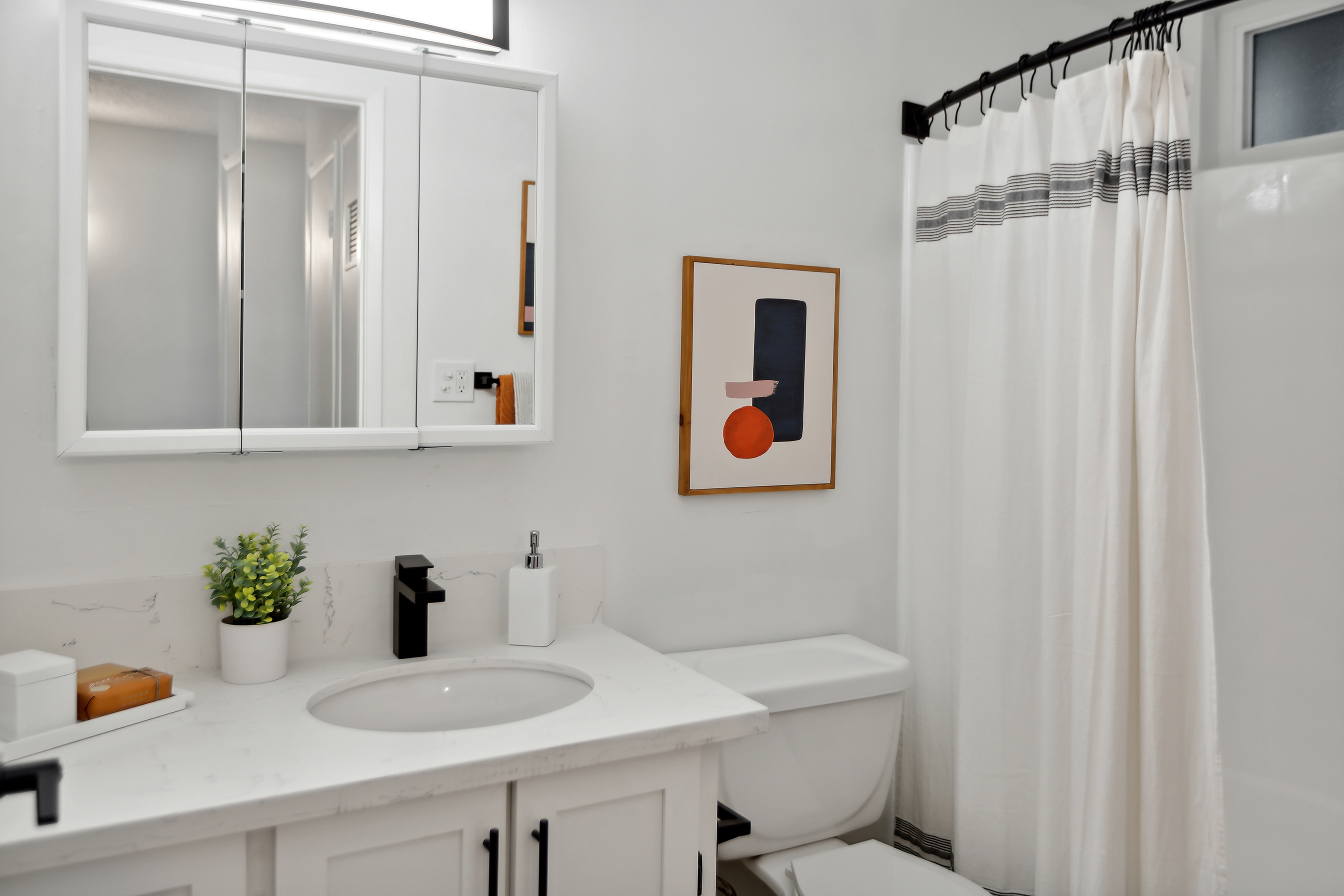 Renovated bathroom with white shaker cabinets and matte black fixtures