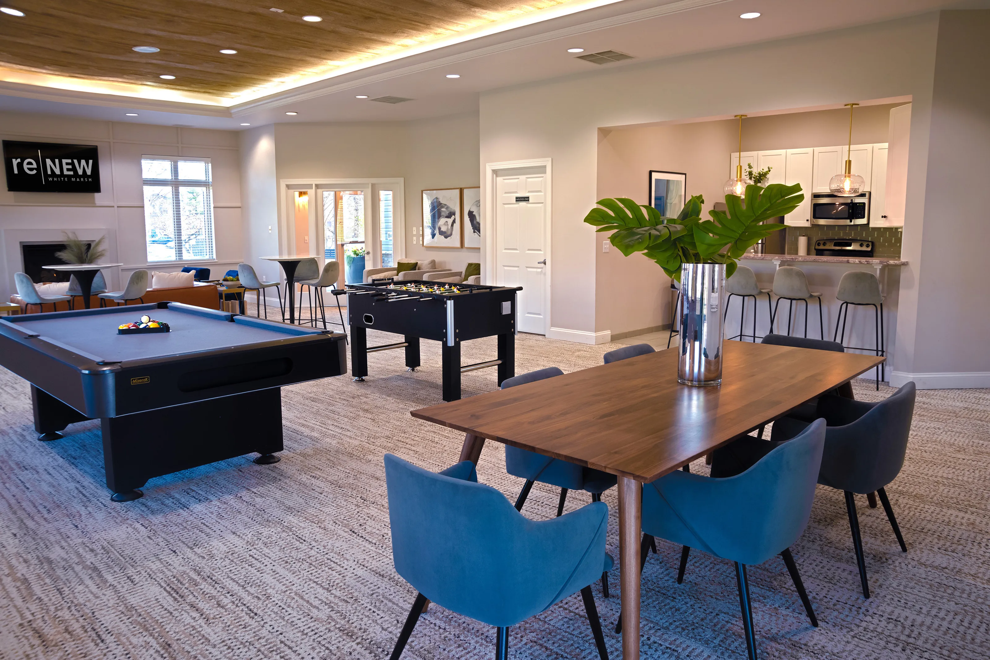 Clubhouse at ReNew White Marsh with dining table, kitchen with barstools, pool table, and foosball table