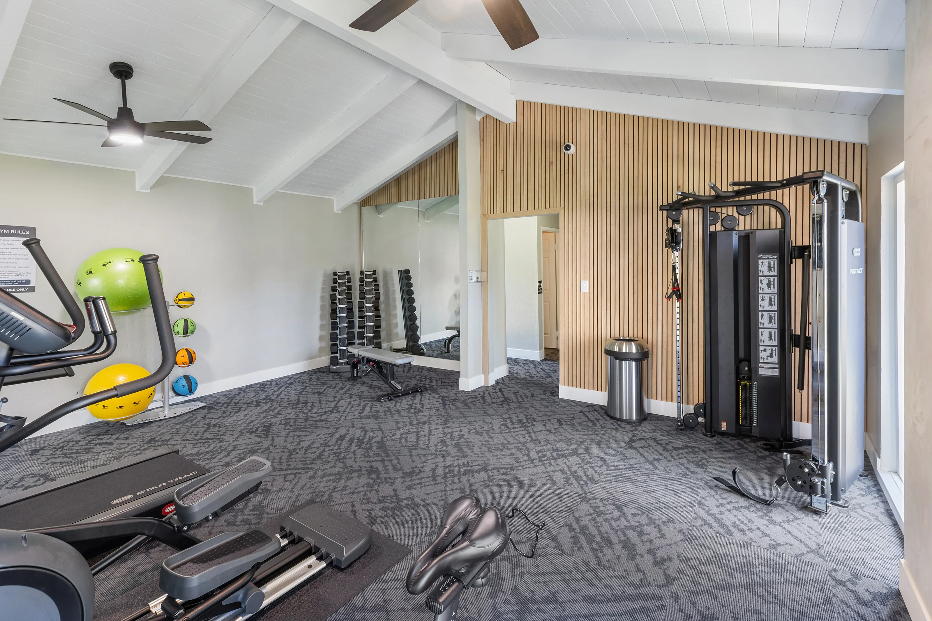 Renovated fitness center with accent wall, weight machines, free weights, and yoga balls