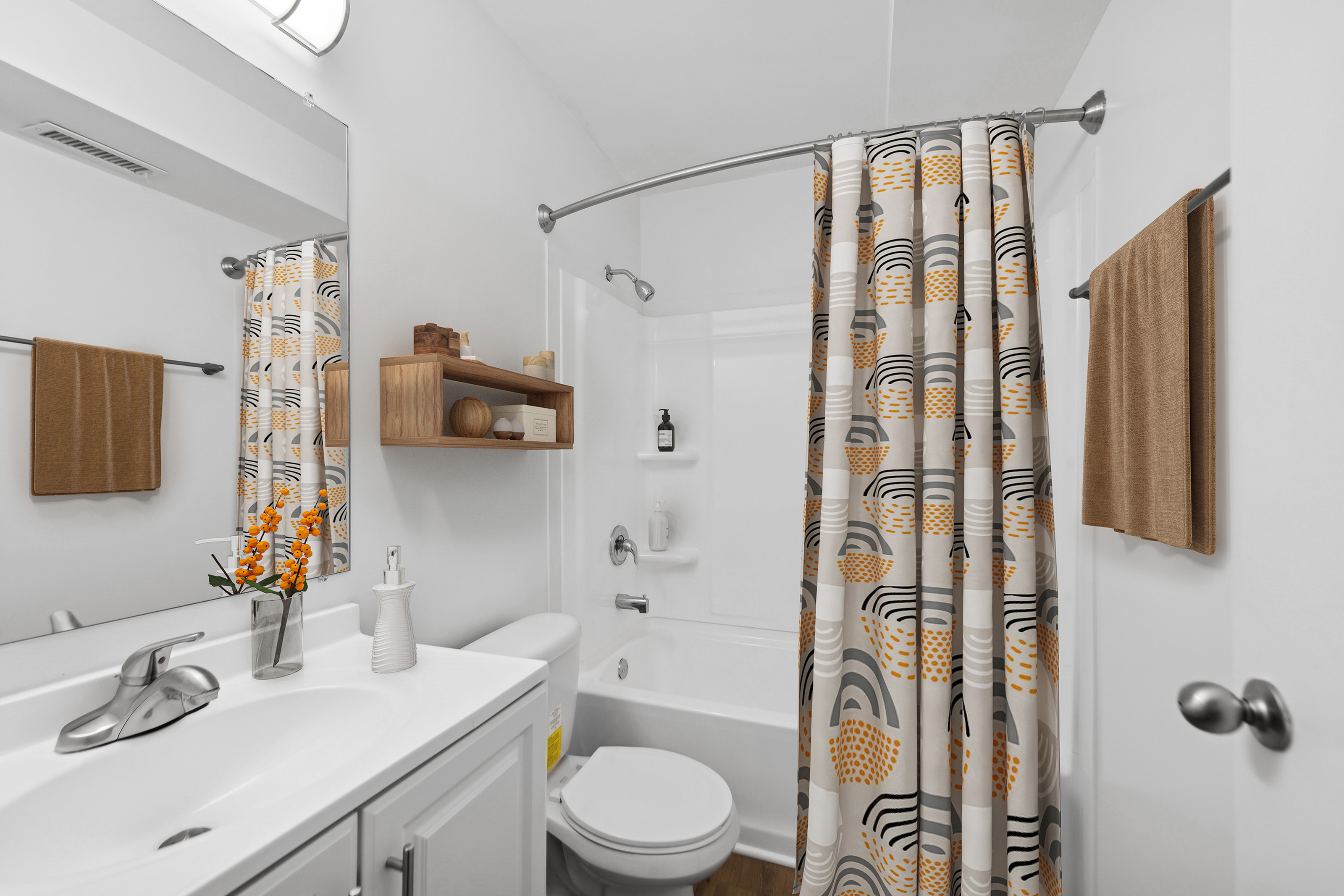 Bright modern bathroom with patterned shower curtain and stylish shelving.