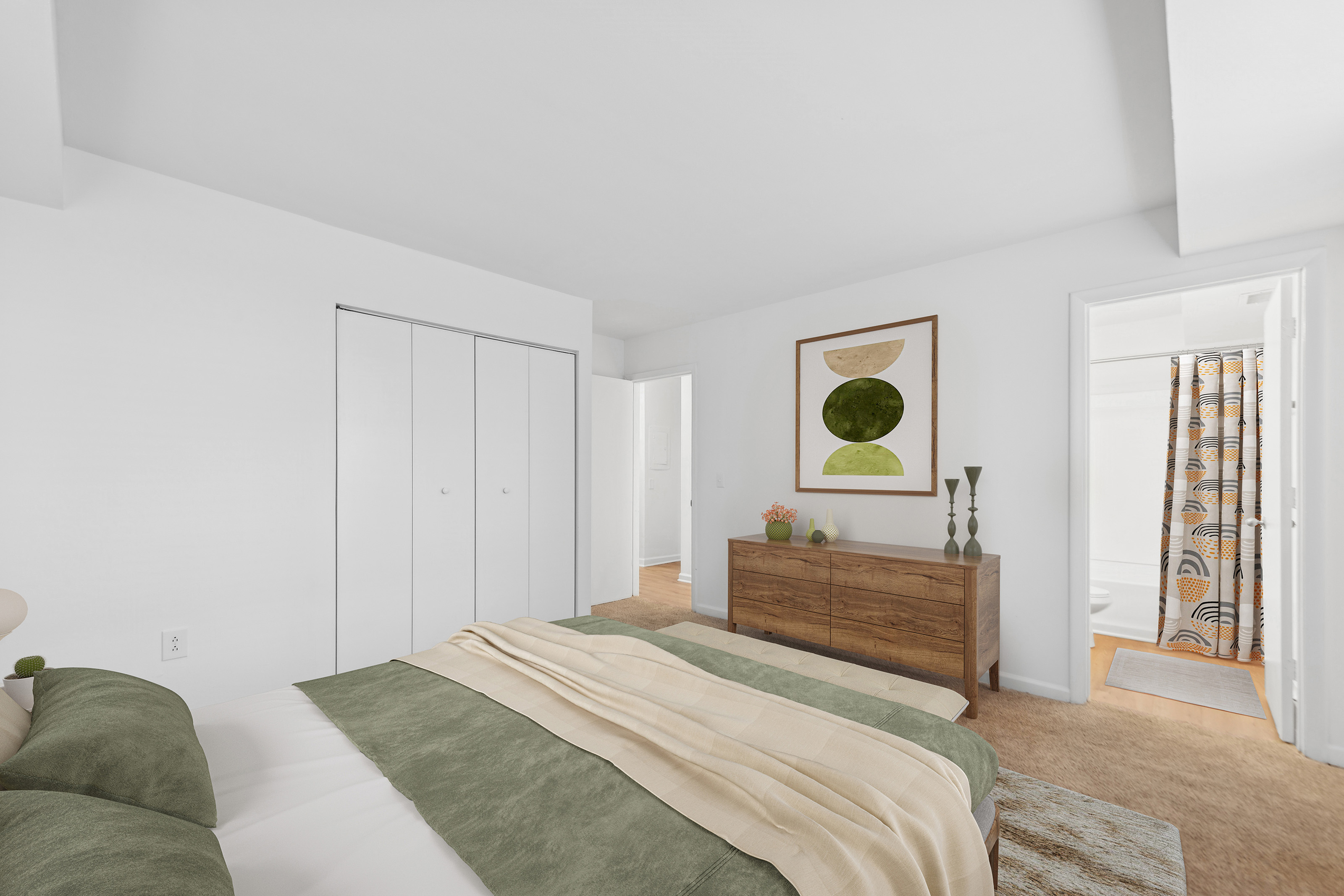 Inviting bedroom with a cozy bed, soft green bedding, wooden dresser, and abstract wall art, leading to a bathroom with a patterned shower curtain.