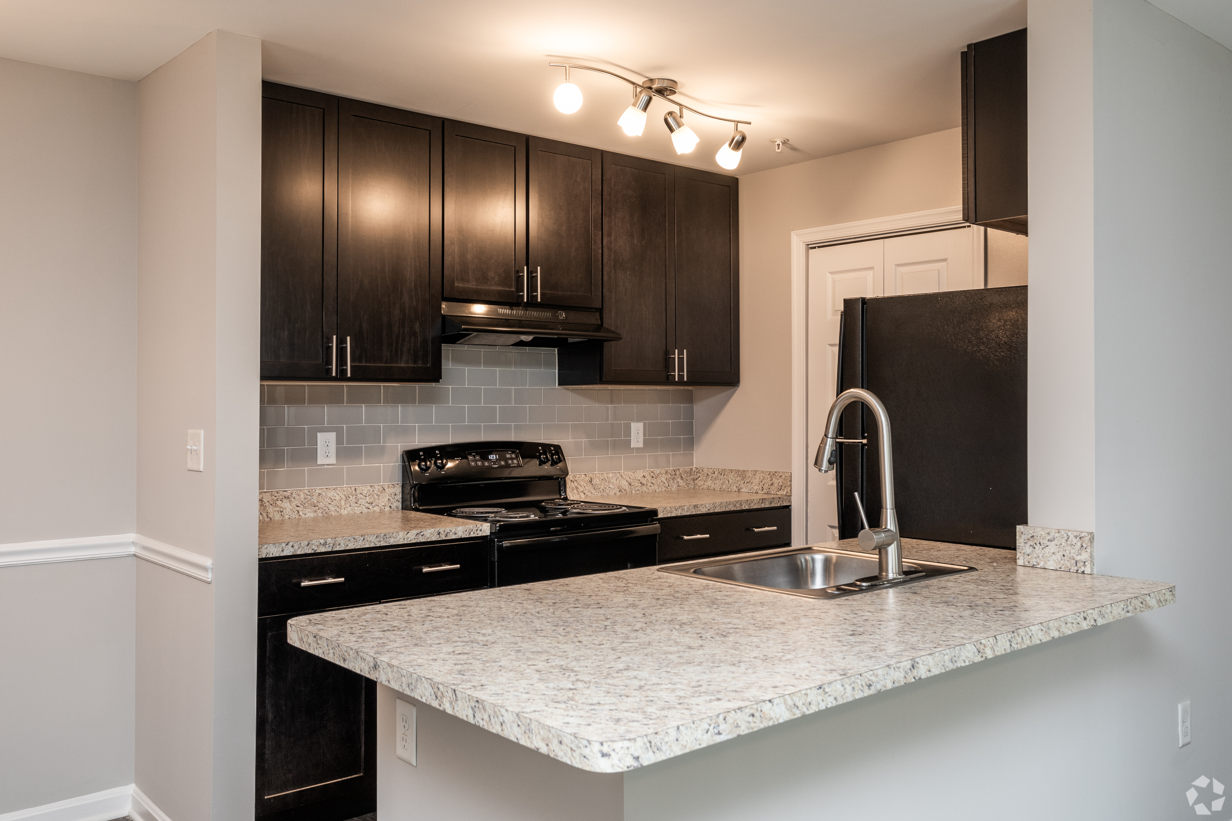 Contemporary kitchen with dark wood cabinets, modern lighting, and a sleek countertop.