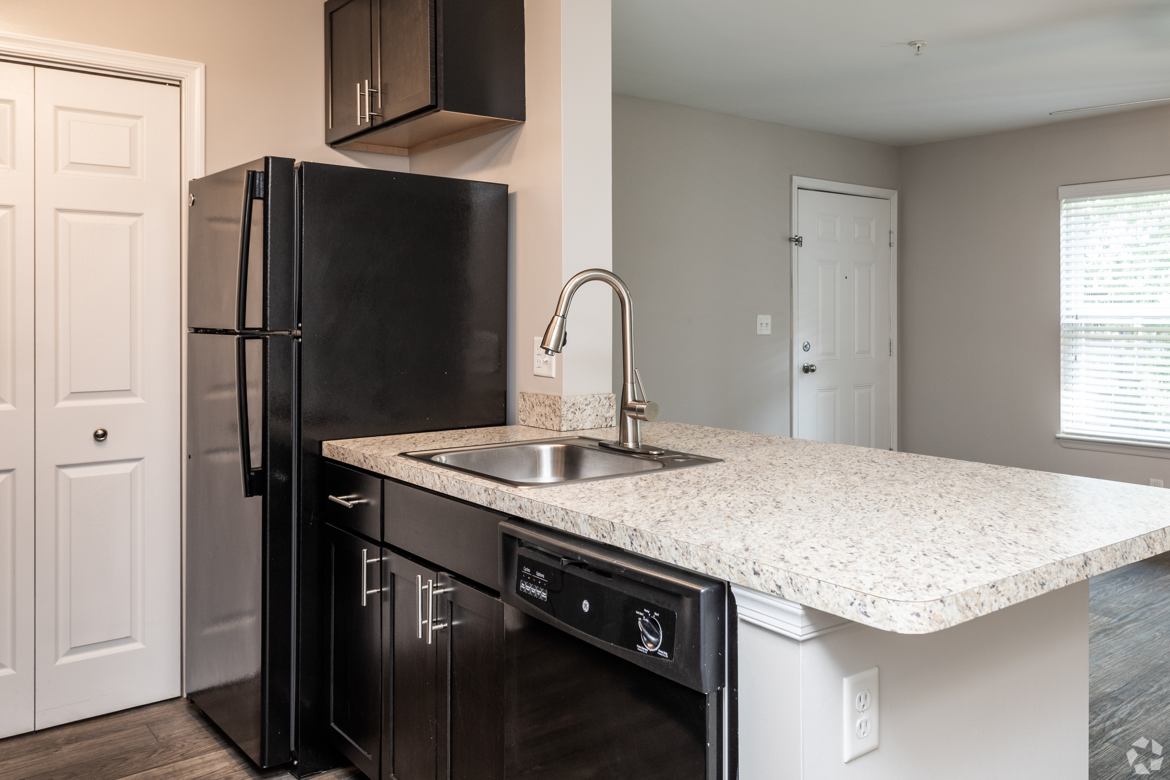 Modern kitchen with black refrigerator, granite countertops, and stainless steel sink.