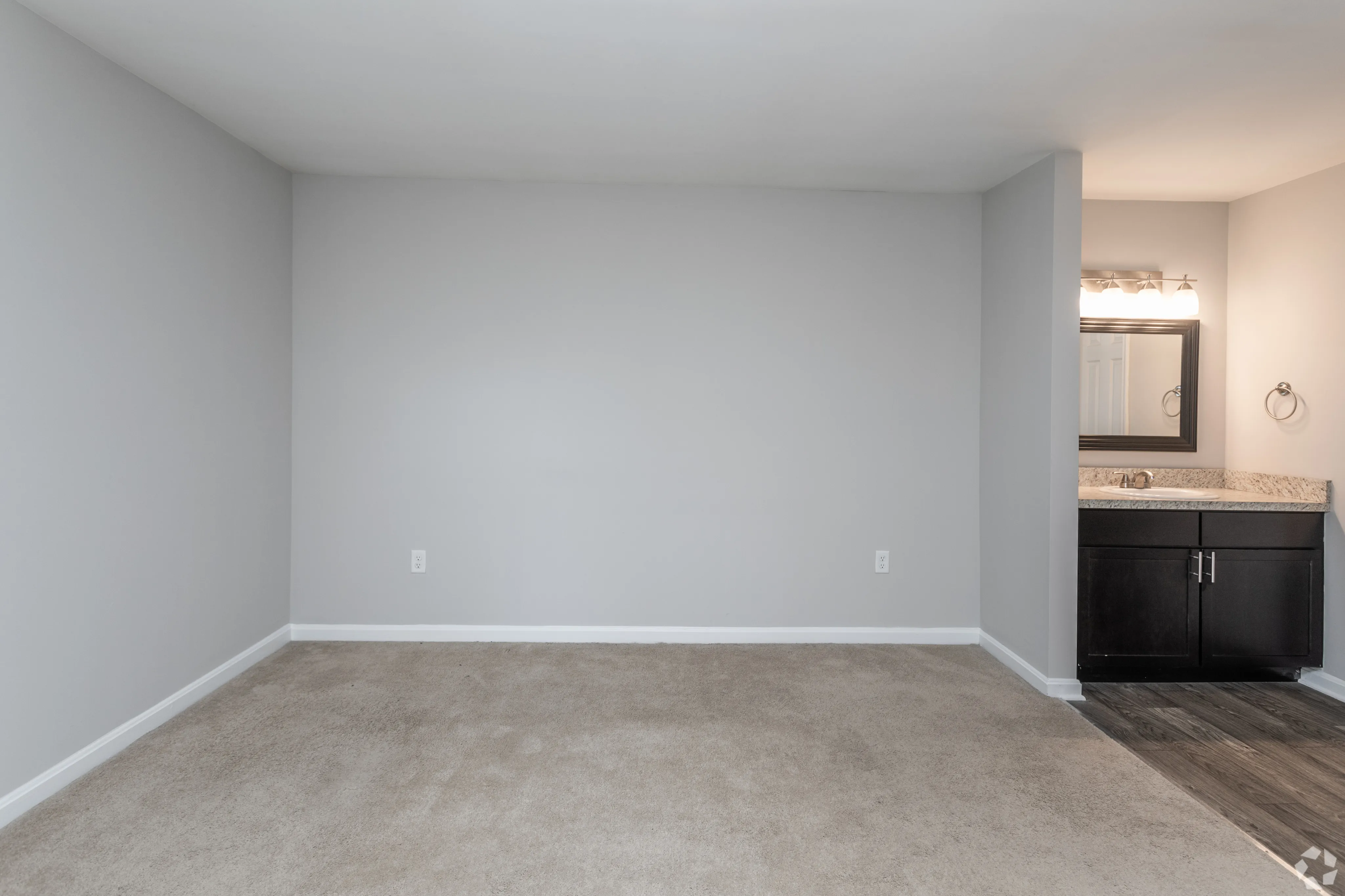 Bright and spacious room featuring a modern vanity area with a large mirror.