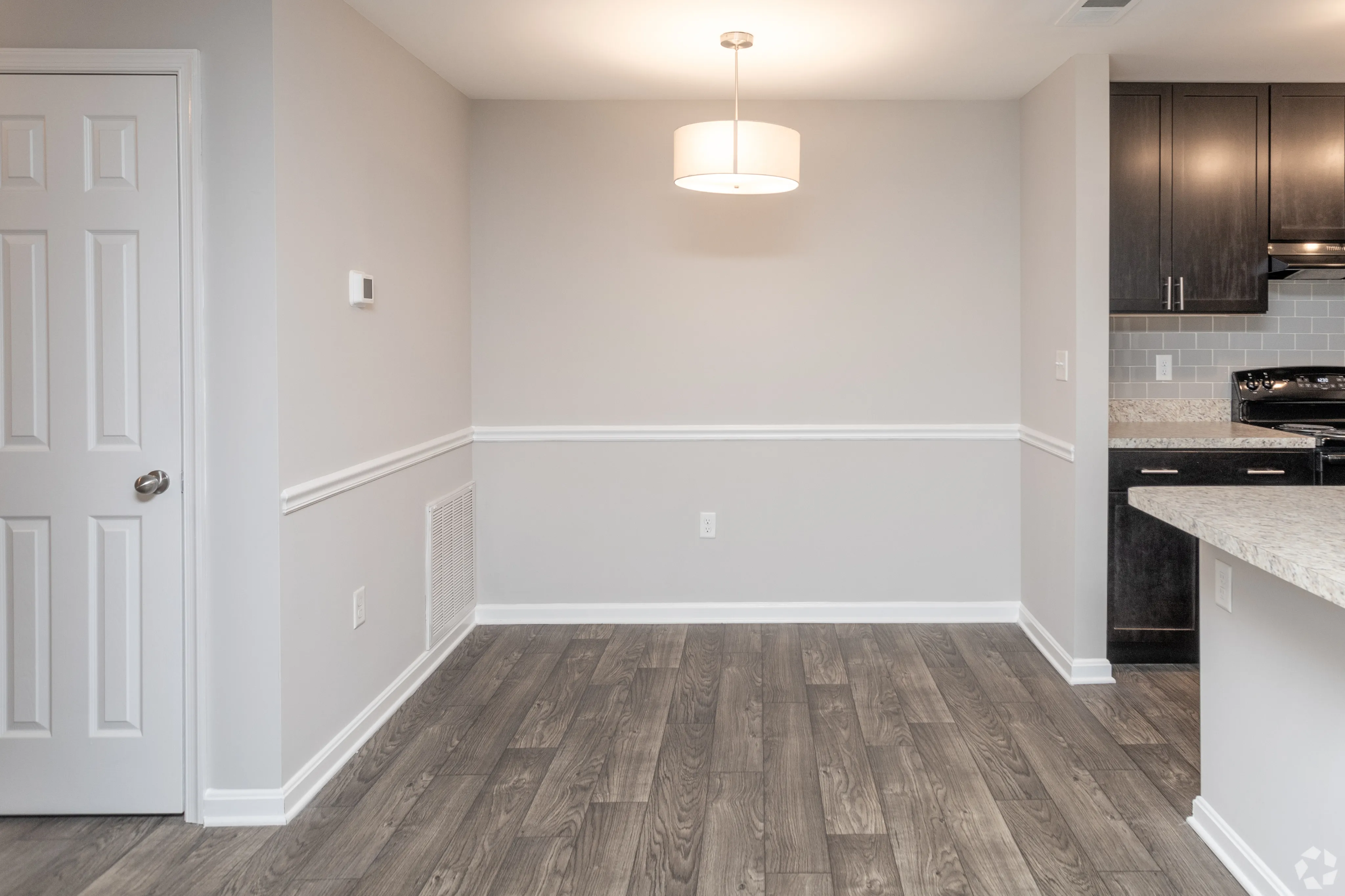 Stylish and minimal dining area with hardwood flooring and modern lighting adjacent to a contemporary kitchen.