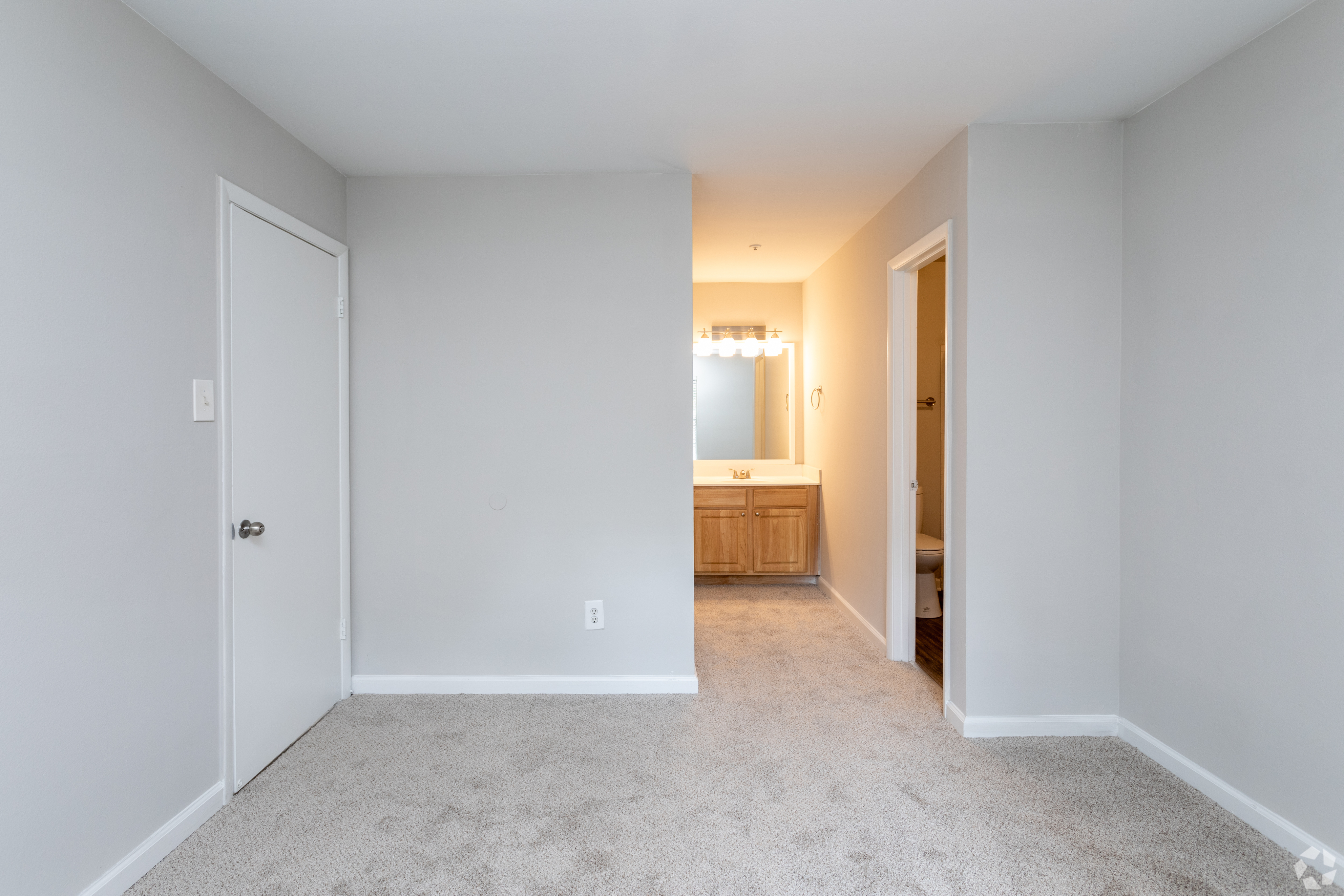 Spacious bedroom with soft carpeting and access to ensuite bathroom.