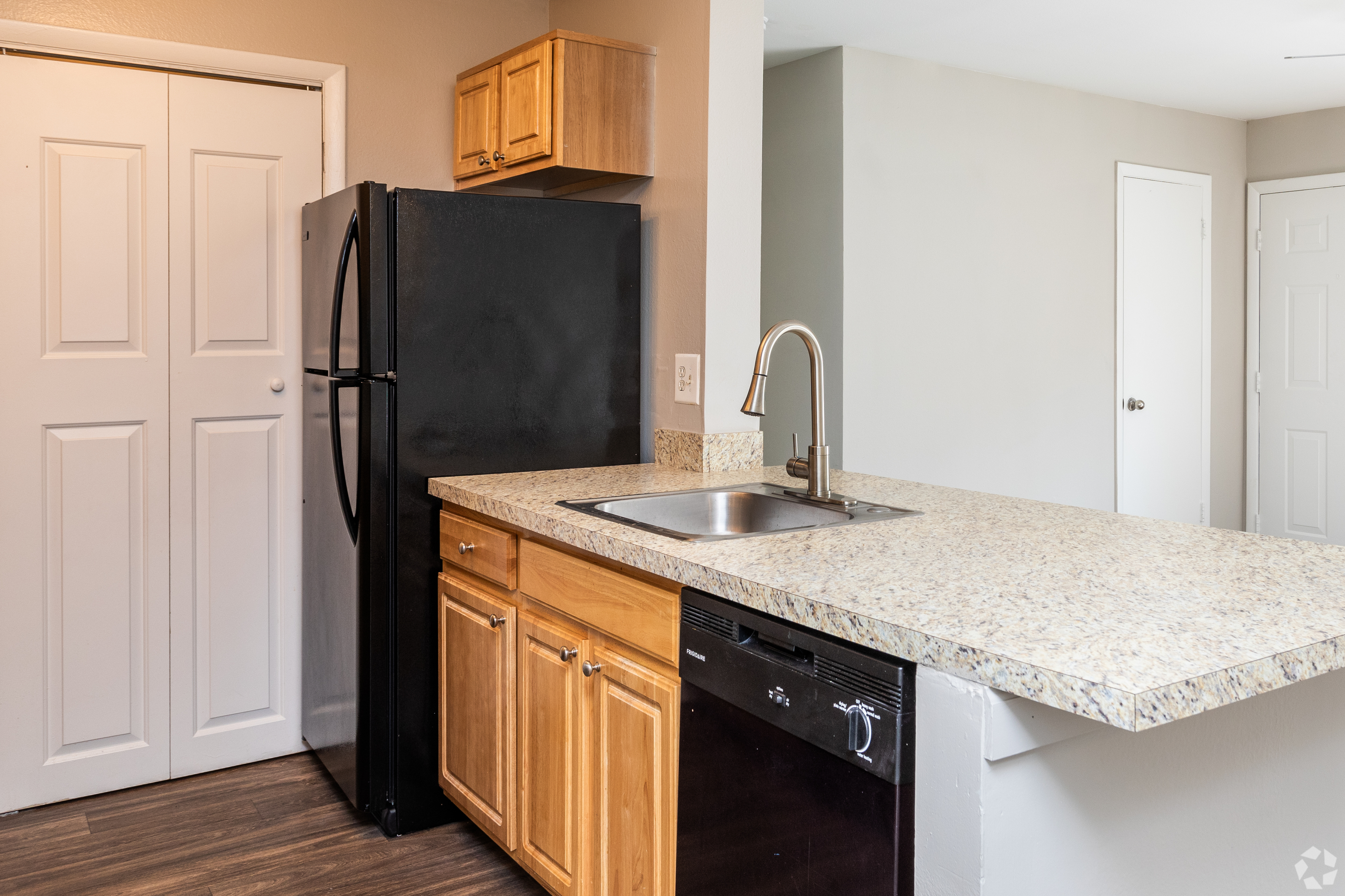 Sleek kitchen with granite countertops, modern sink, and dark refrigerator.