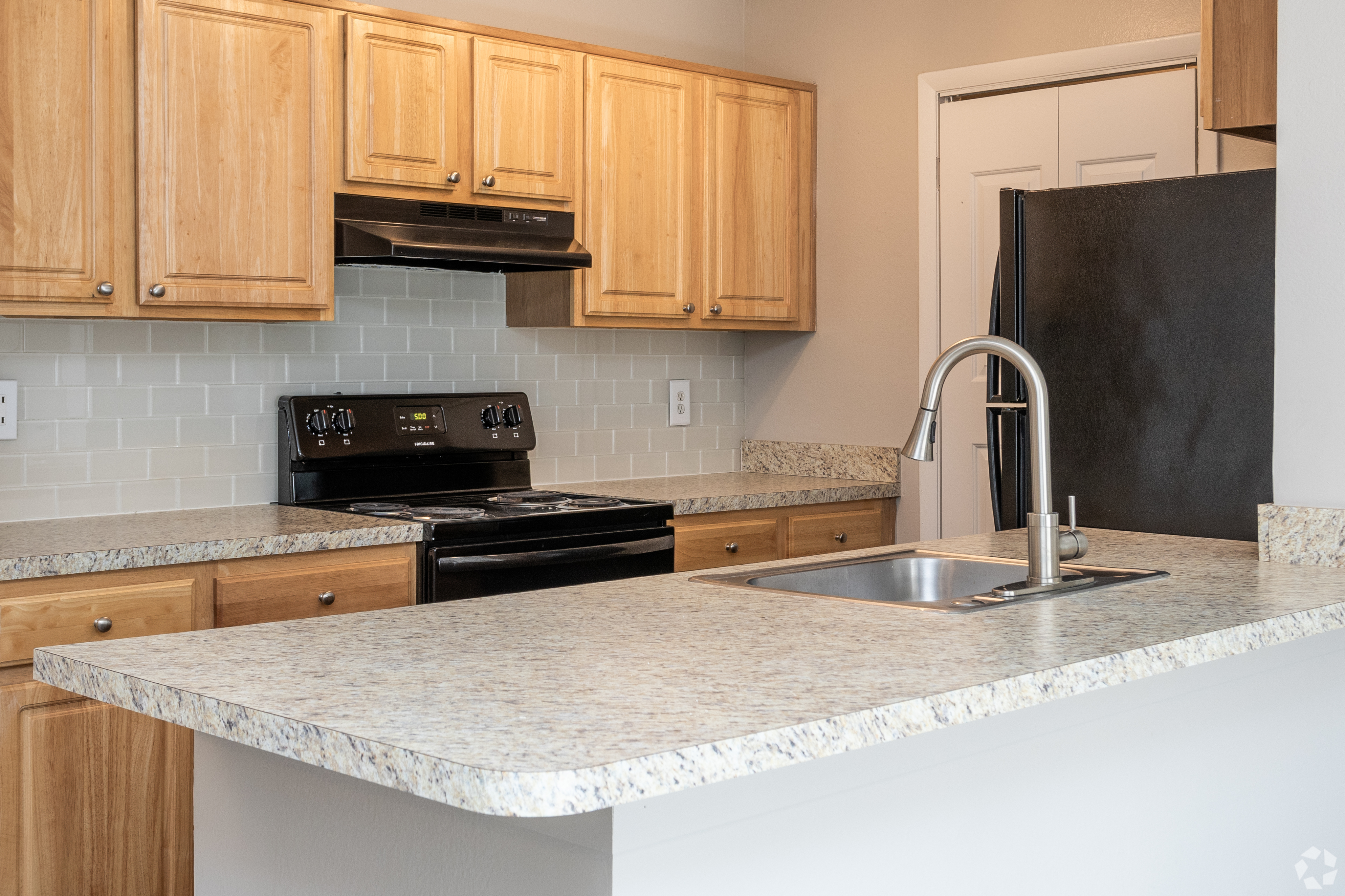 Modern kitchen with light wooden cabinets, granite countertops, and stainless steel appliances.