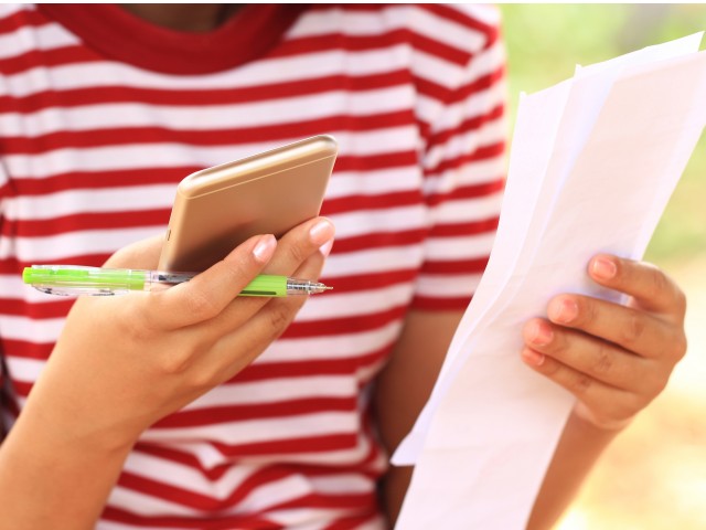 Person holding phone, pen, and receipts