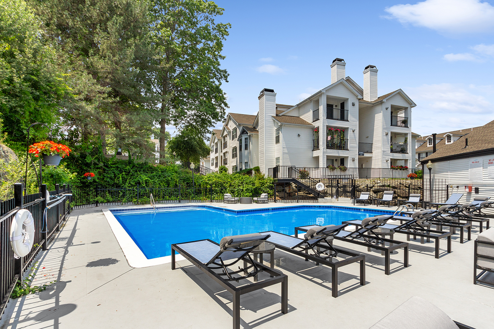 Inviting residential complex with a pristine pool, surrounded by lush greenery and elegant multi-story buildings offering a serene retreat.