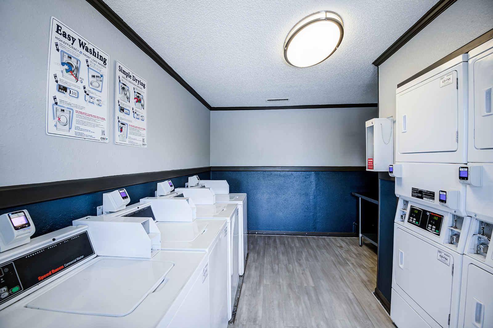 Modern laundry room with multiple washing and drying machines, featuring sleek design and user-friendly interfaces.