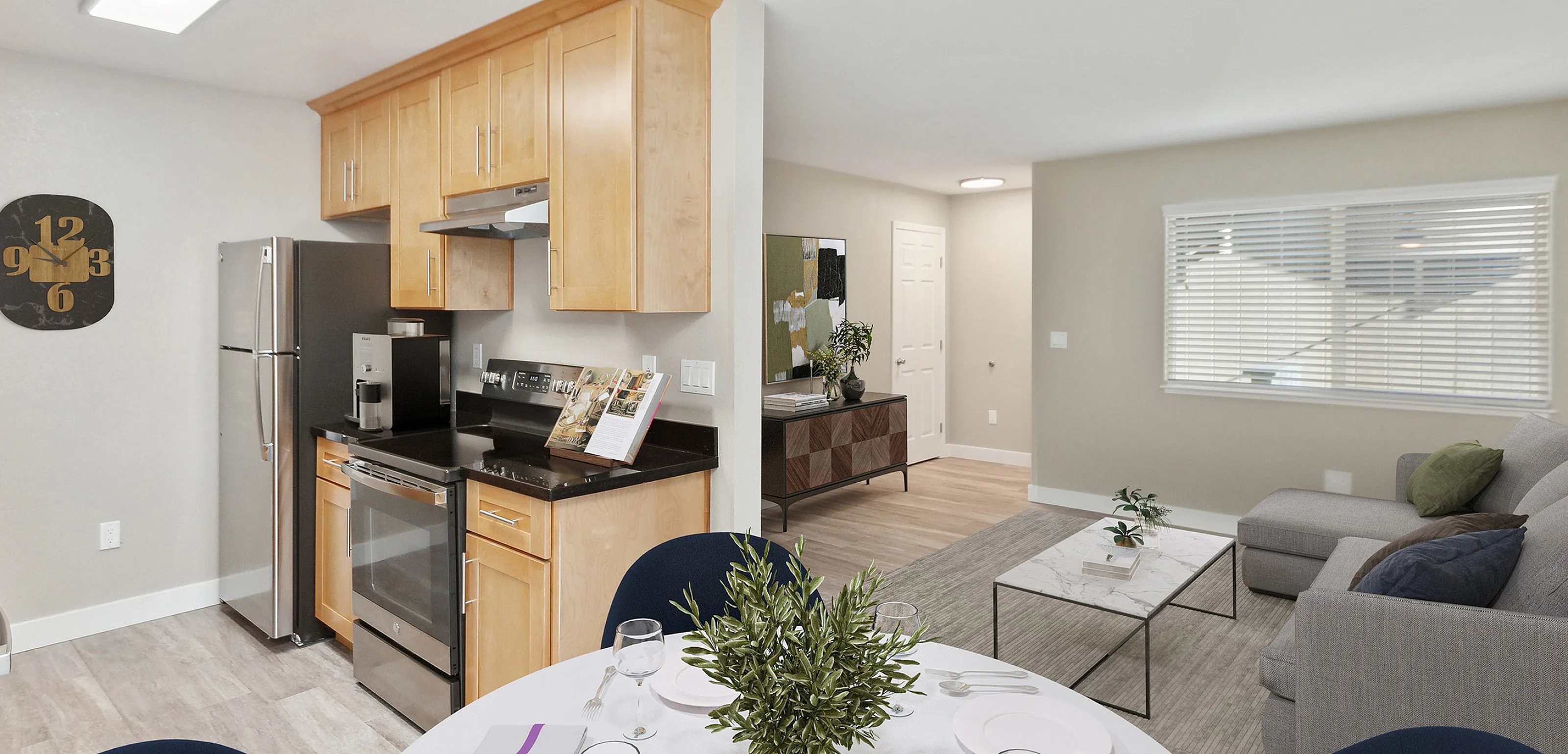 Modern apartment with open-plan kitchen, dining area set for four, and cozy living room with natural light.