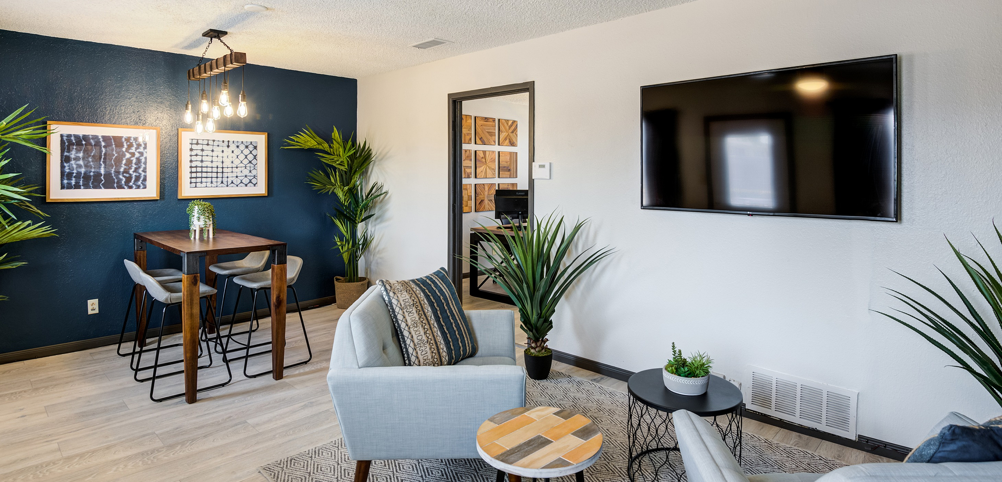 Modern living room with a ceiling fan, wall-mounted TV, stylish decor, and adjacent dining area.