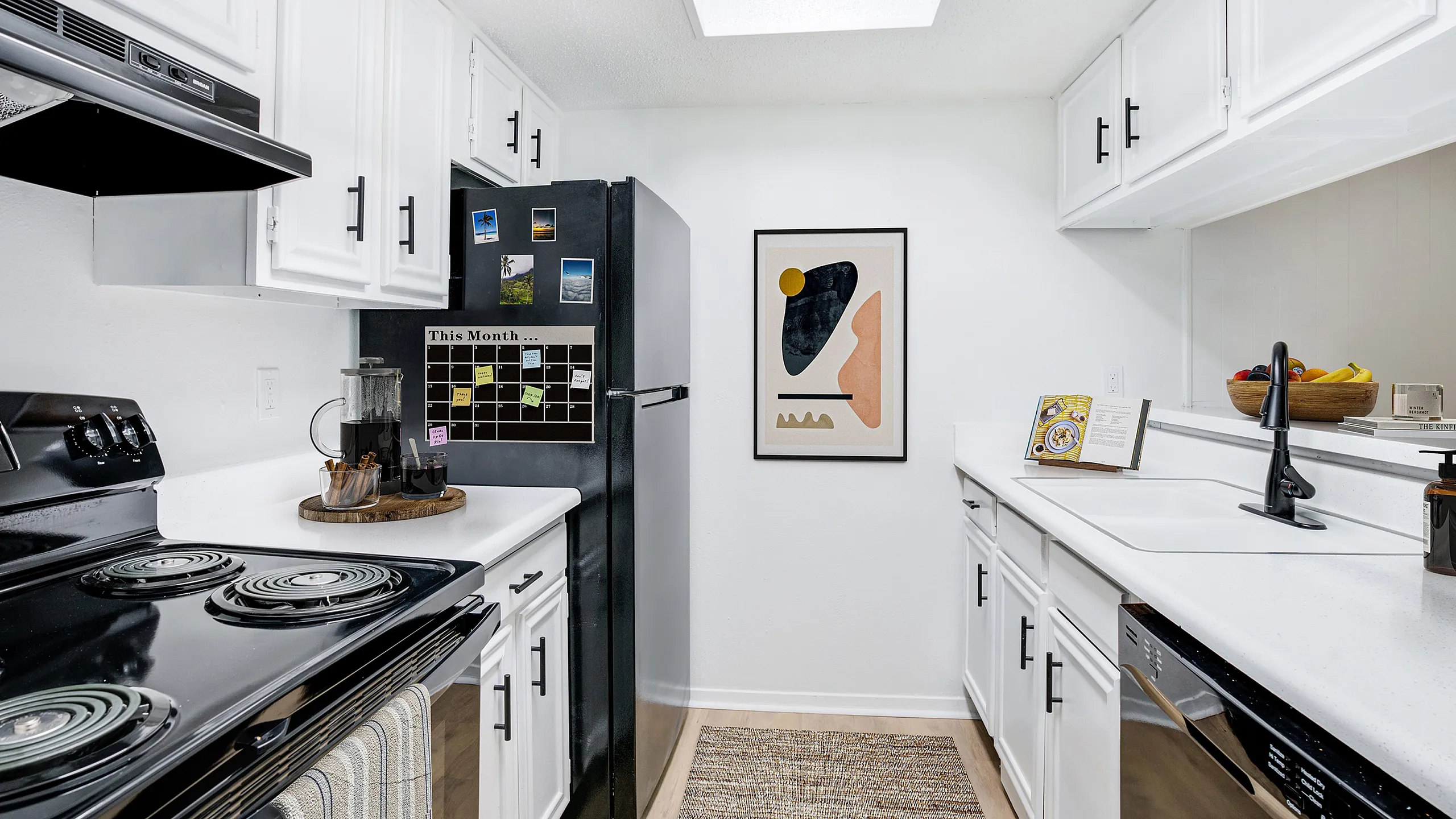Chic, modern kitchen with sleek white cabinetry, black appliances, and stylish decor, offering a bright and inviting space for culinary inspiration.
