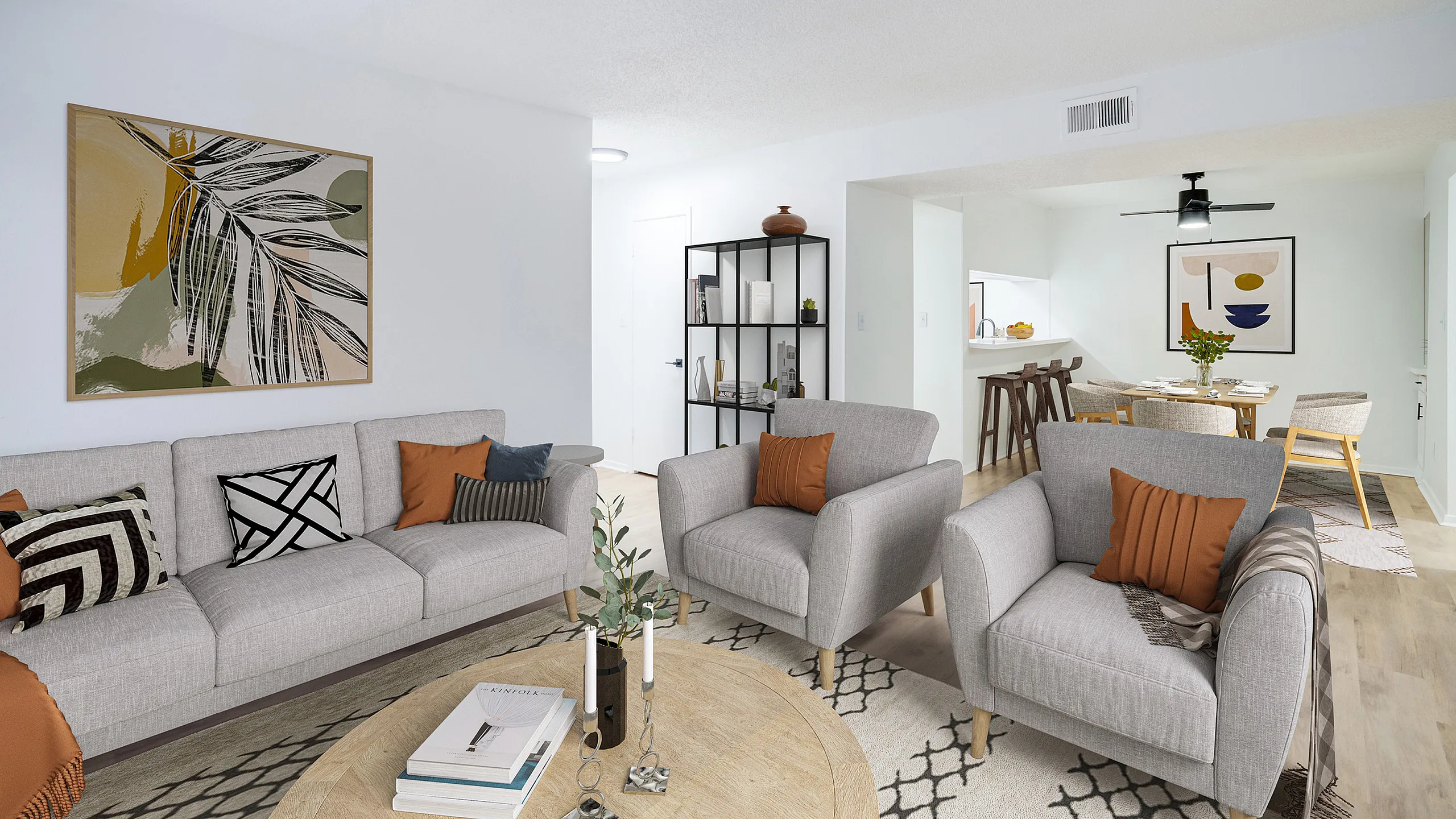 Modern living space with cozy gray sofas accented by earthy pillows, elegant artwork, and a sleek open-concept dining area adjacent to a chic kitchen.