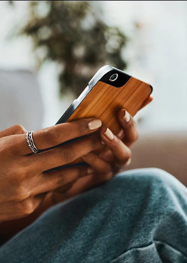 Cozy living room setting with a person holding a stylishly designed smartphone, conveying a modern and comfortable lifestyle.