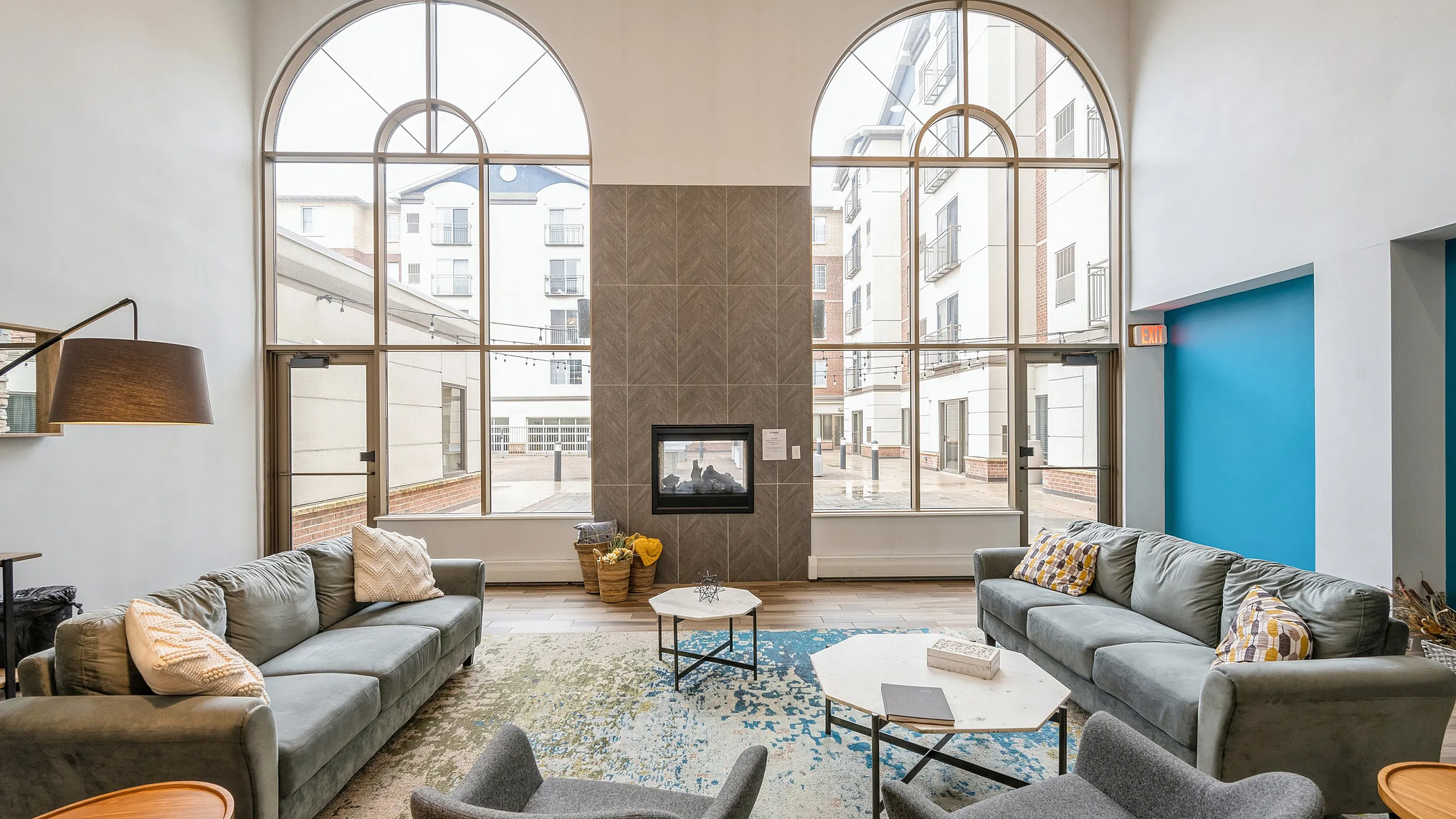 Elegant and spacious living area featuring modern sofas, large arched windows with ample natural light, and a cozy fireplace, perfect for relaxation.