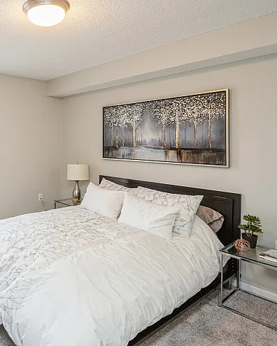 Charming bedroom with a cozy bed, stylish decor, large window, and elegant artwork, perfect for relaxation.