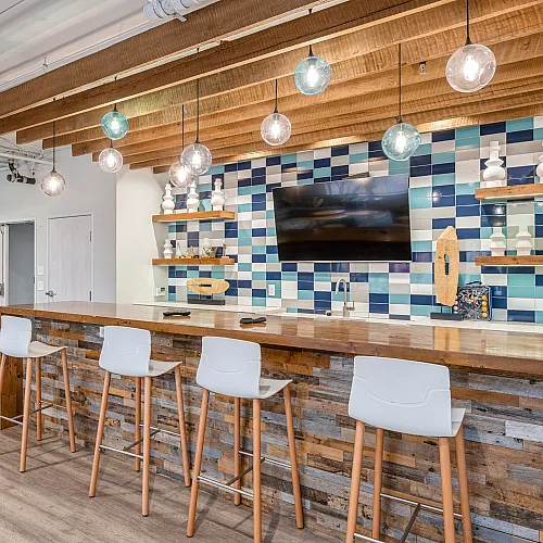 Chic modern kitchen with stylish bar seating, vibrant tiled backsplash, and elegant pendant lighting.