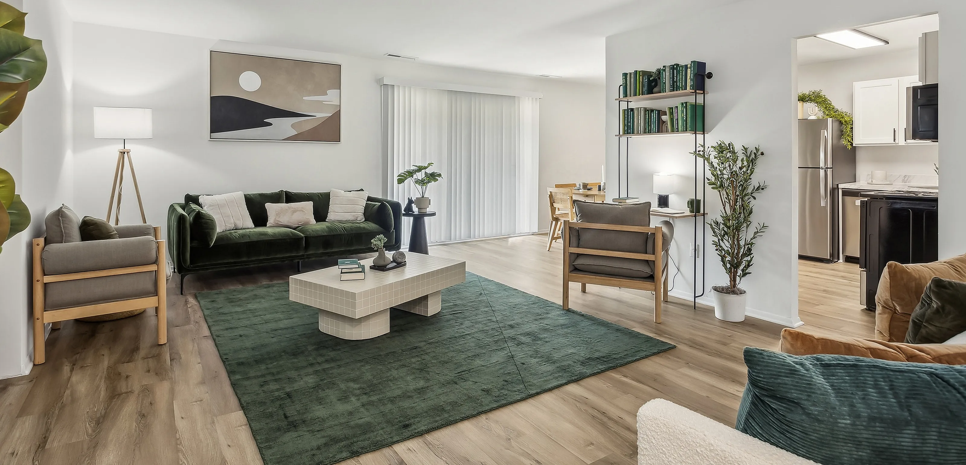 Bright and modern living room with elegant green accents, showcasing a cozy seating area, chic coffee table, and open layout leading to a dining space and kitchen.
