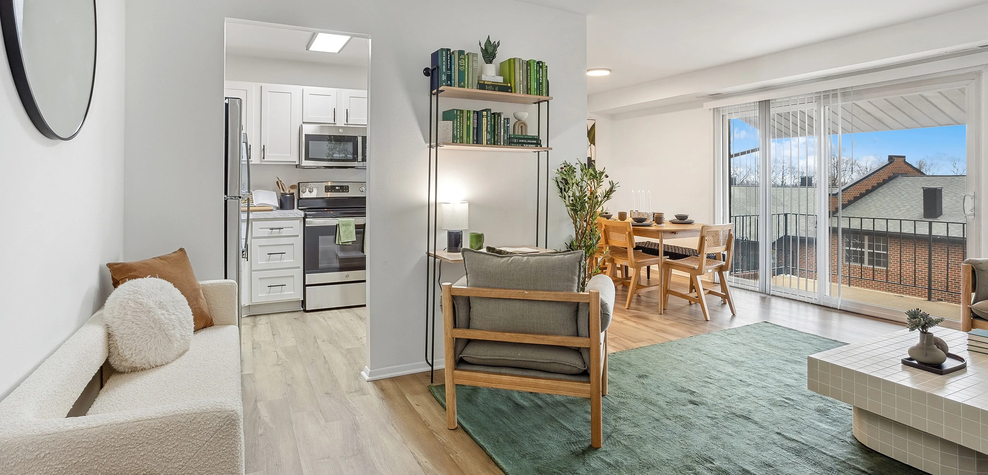 Bright, modern open-concept living space featuring a stylish kitchen, cozy dining area, and spacious living room with floor-to-ceiling windows leading to a balcony view.