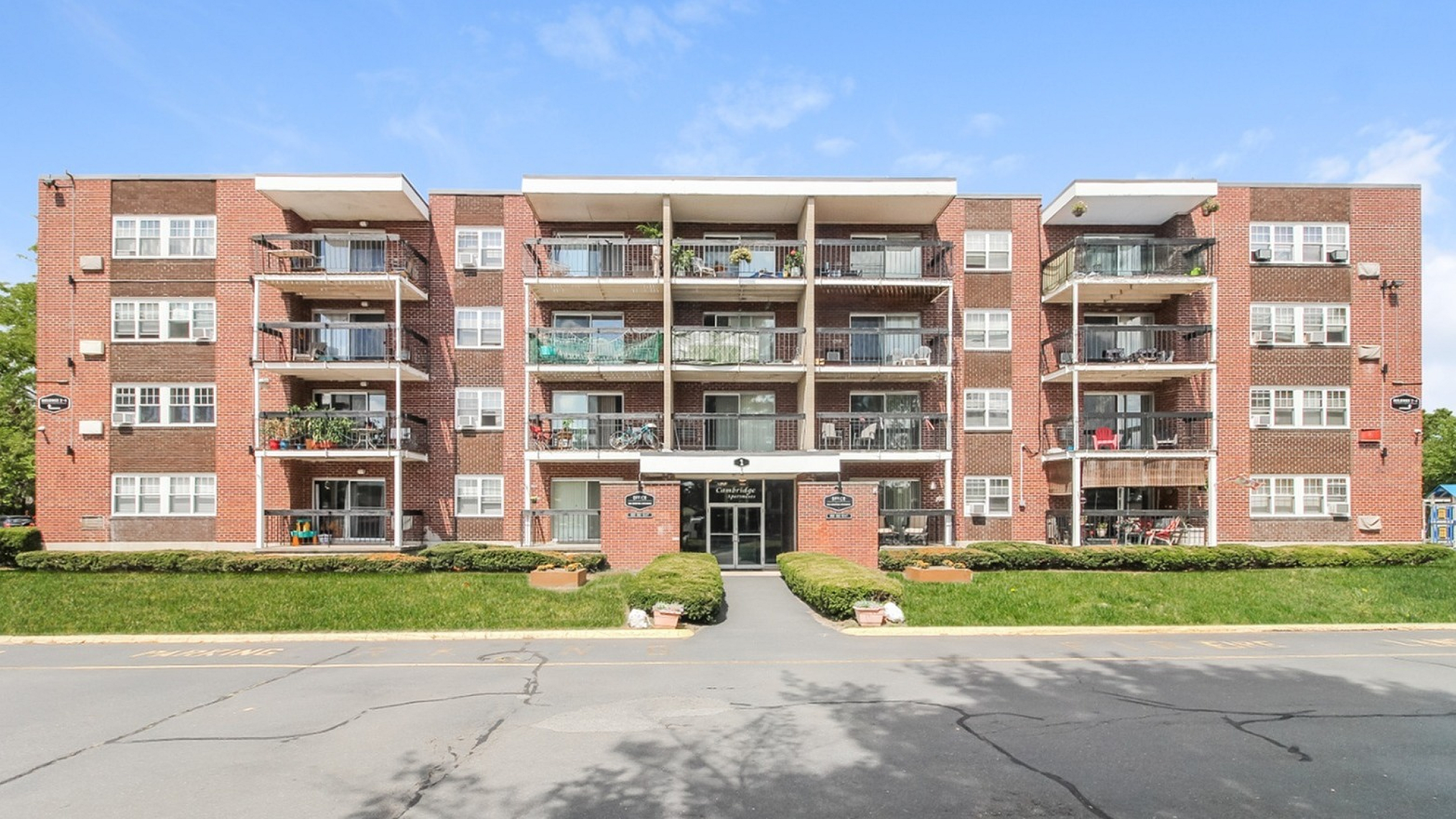 Charming red-brick apartment building with spacious balconies and well-maintained green surroundings, perfect for a serene living experience.