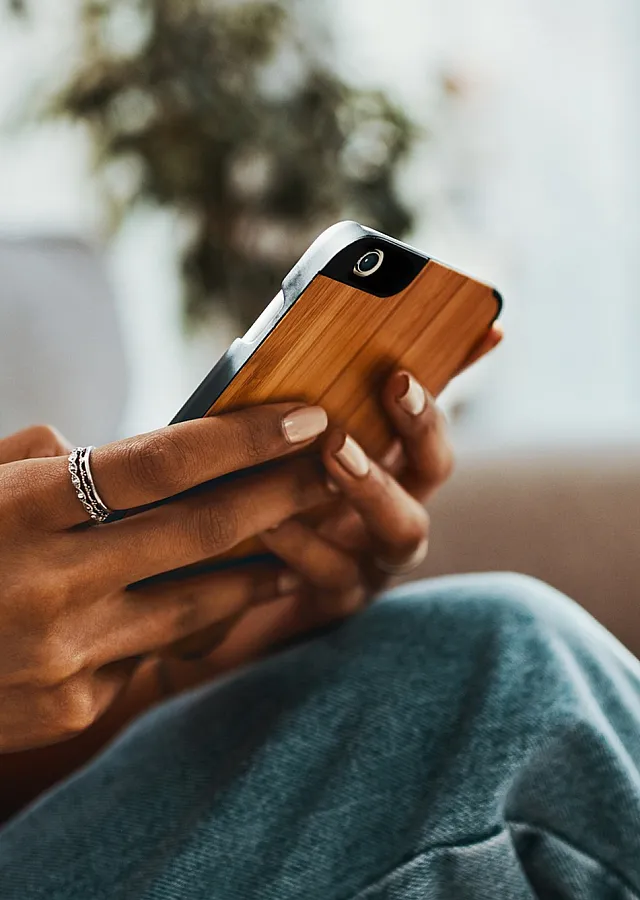 Close-up of a person sitting comfortably on a couch while using a smartphone, emphasizing relaxation and modern living.