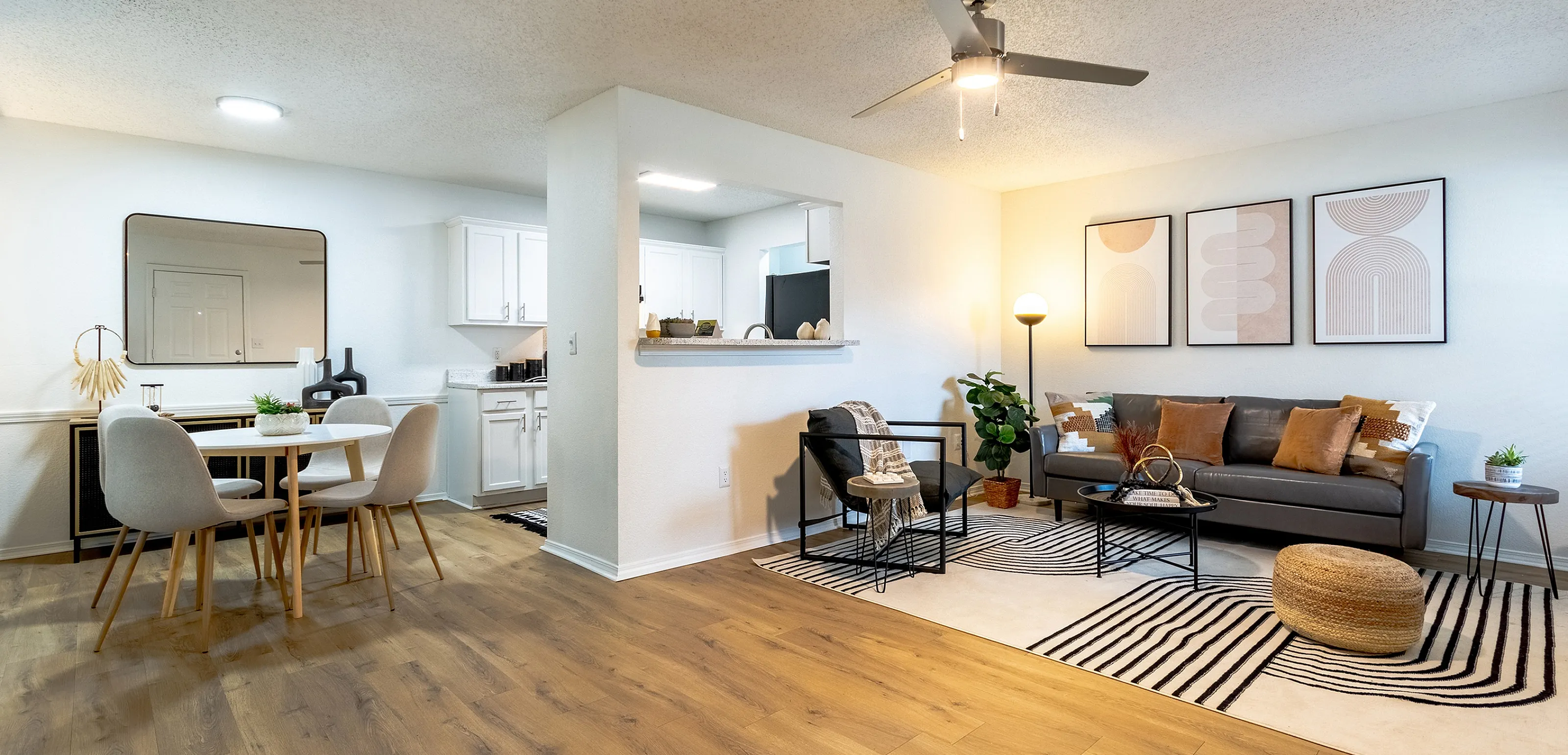 Inviting open-concept living space featuring modern decor, hardwood floors, a stylish sofa, dining area, and contemporary kitchen.