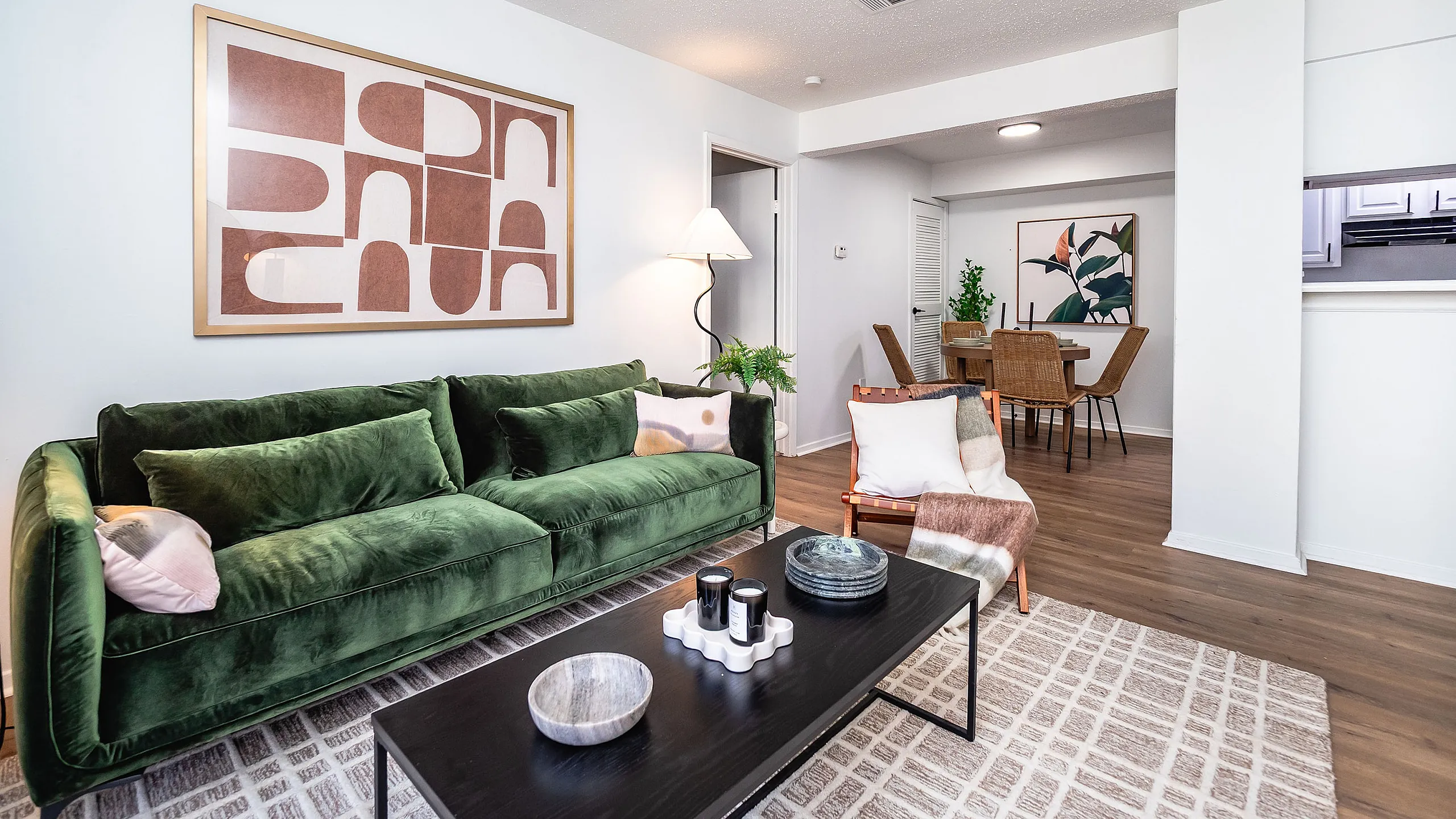 Sophisticated living room featuring a plush green sofa, chic modern art, and an elegant dining area with stylish decor.